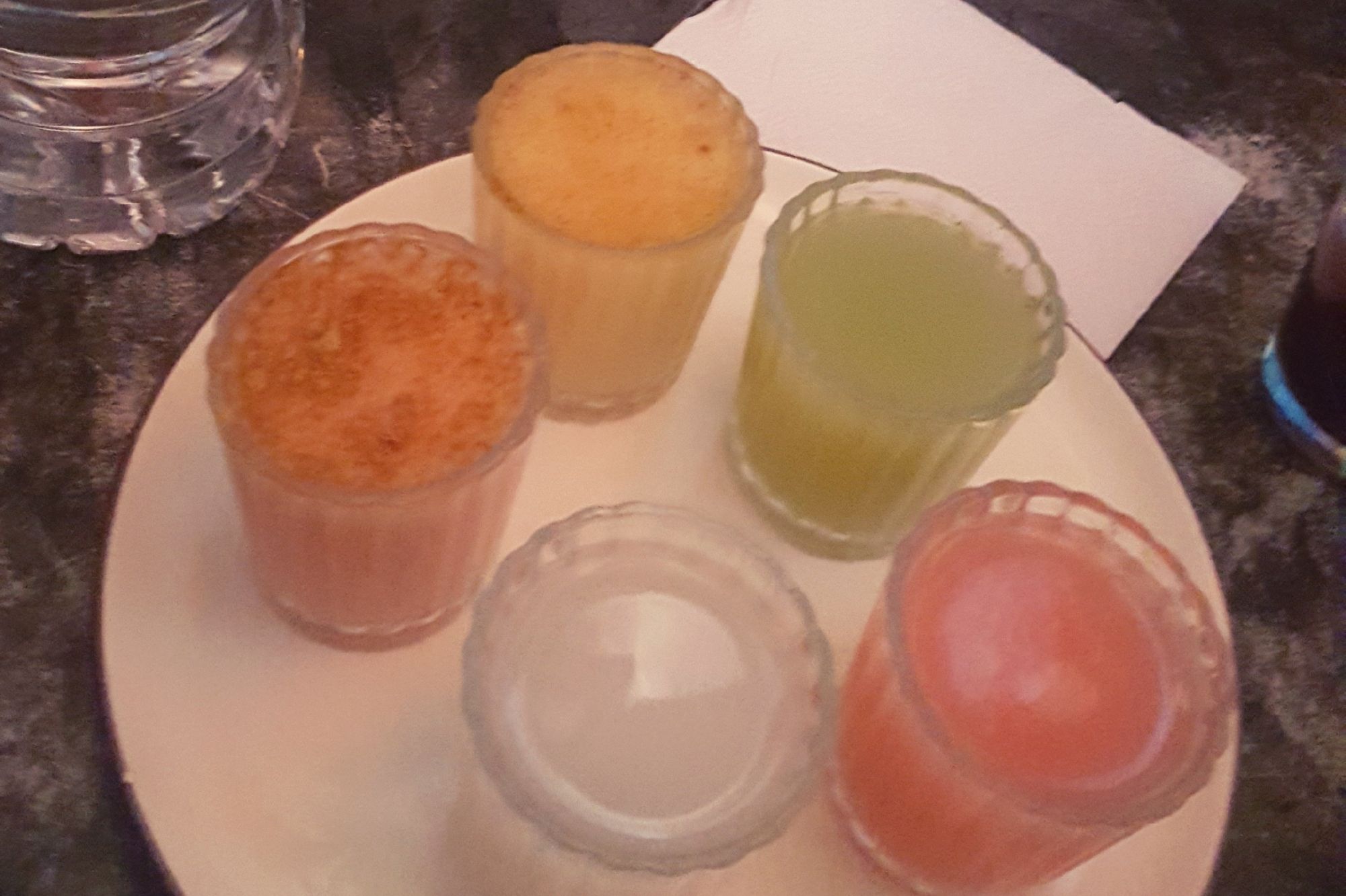 Sampler of brightly colored pulque beverages in small glasses