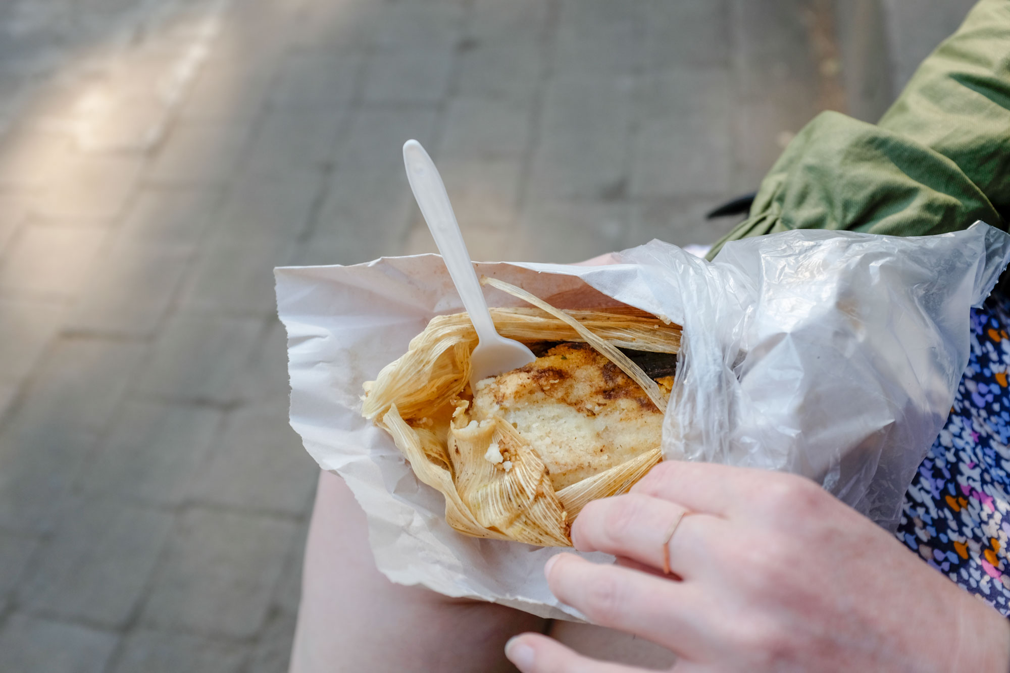 Alyssa holding a tamale with a fork placed inside