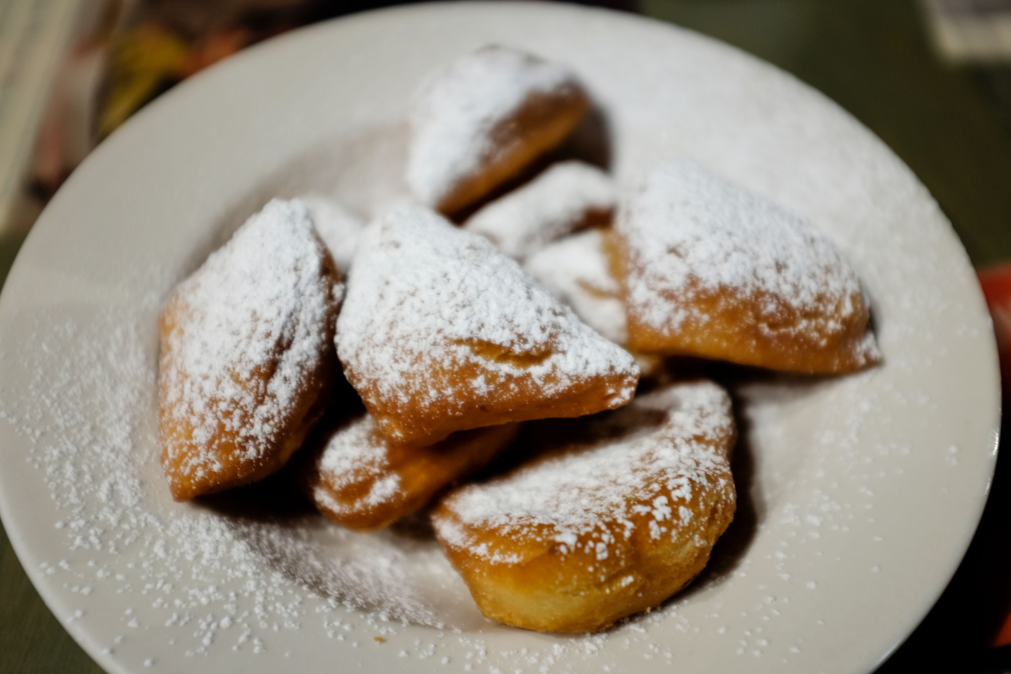 a plate of beignets topped with powdered sugar