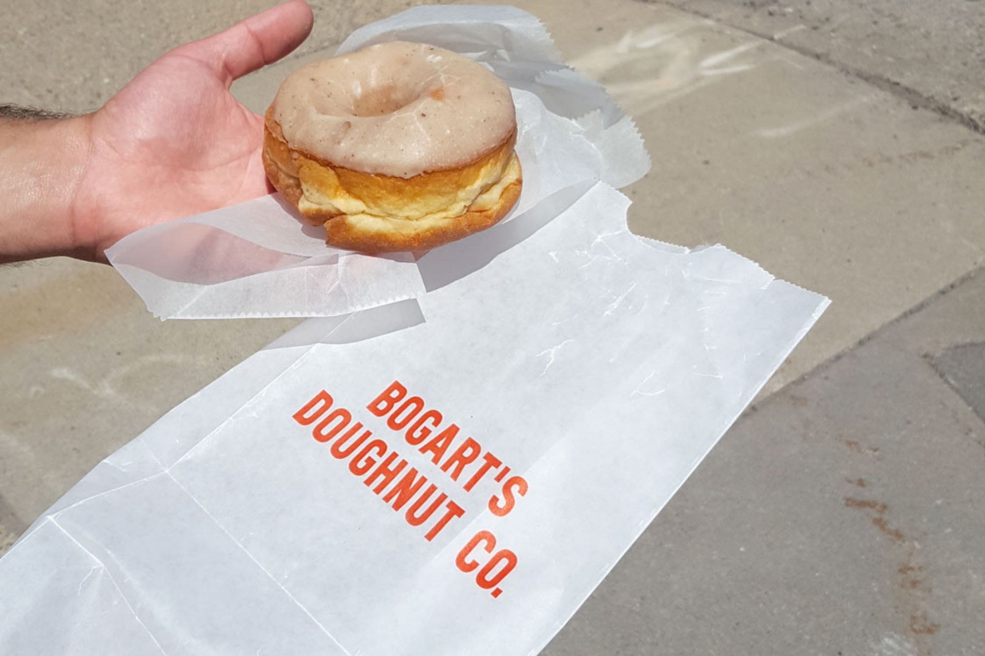 Michael holding a doughnut over a bag branded with the shop's name