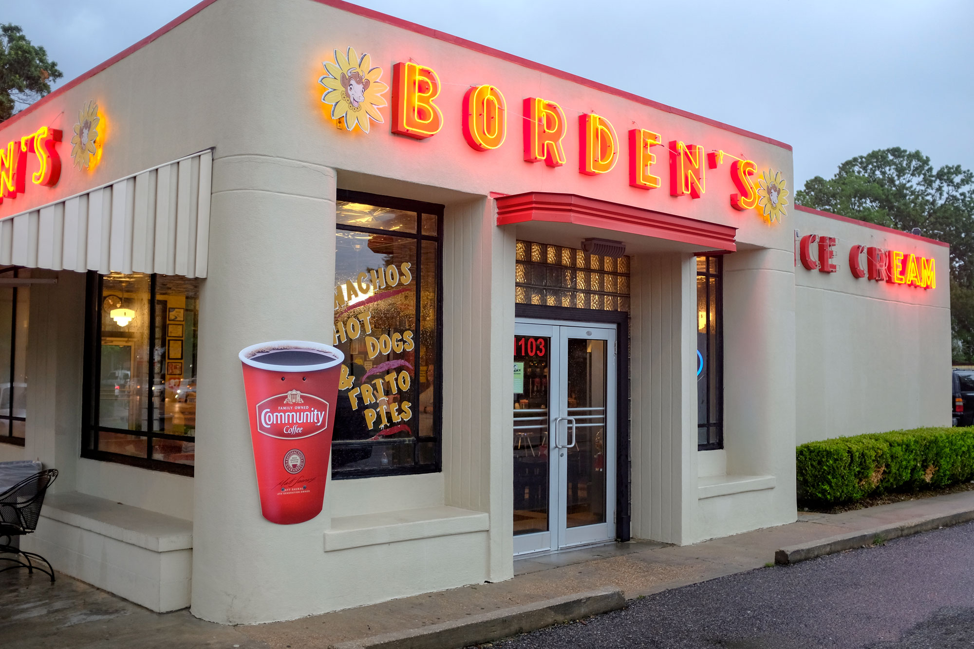 Exterior of Borden's Ice Cream. It's a very retro-looking building with "Borden's" in neon lights and the company's logo (a cow's face in the center of a flower)