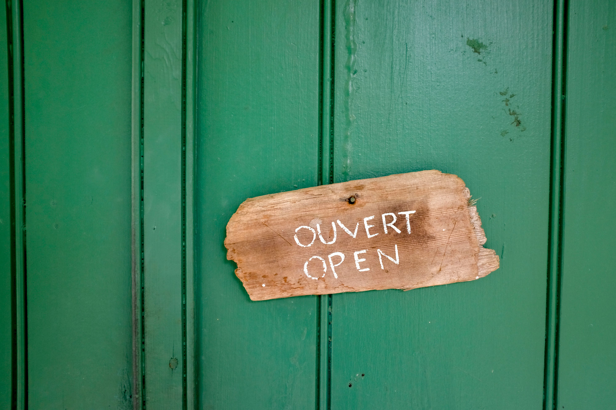 A green door with a sign on it that says "ouvert" and "open"