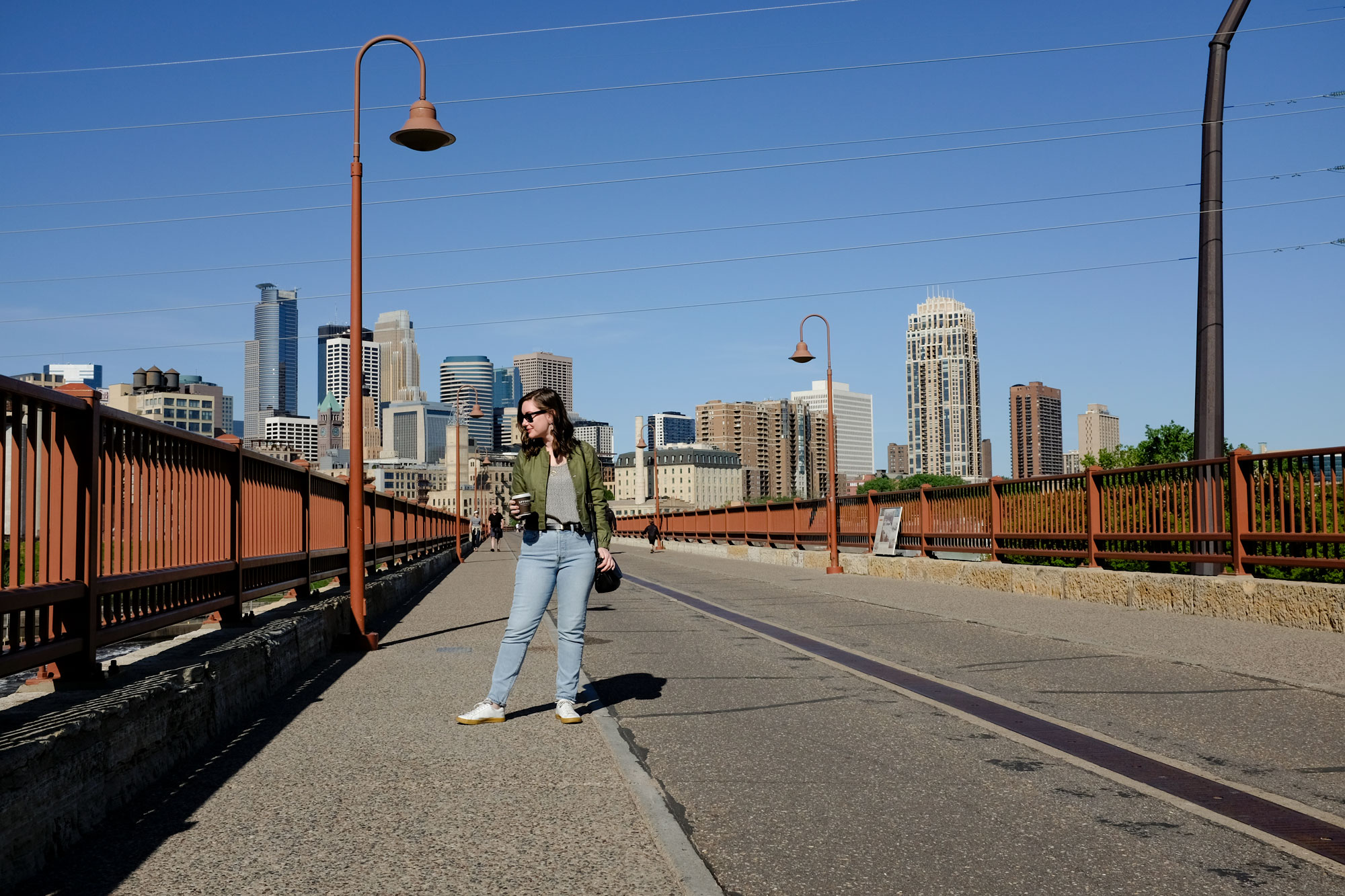 Alyssa standing on a bridge with downtown minneapolis in the background