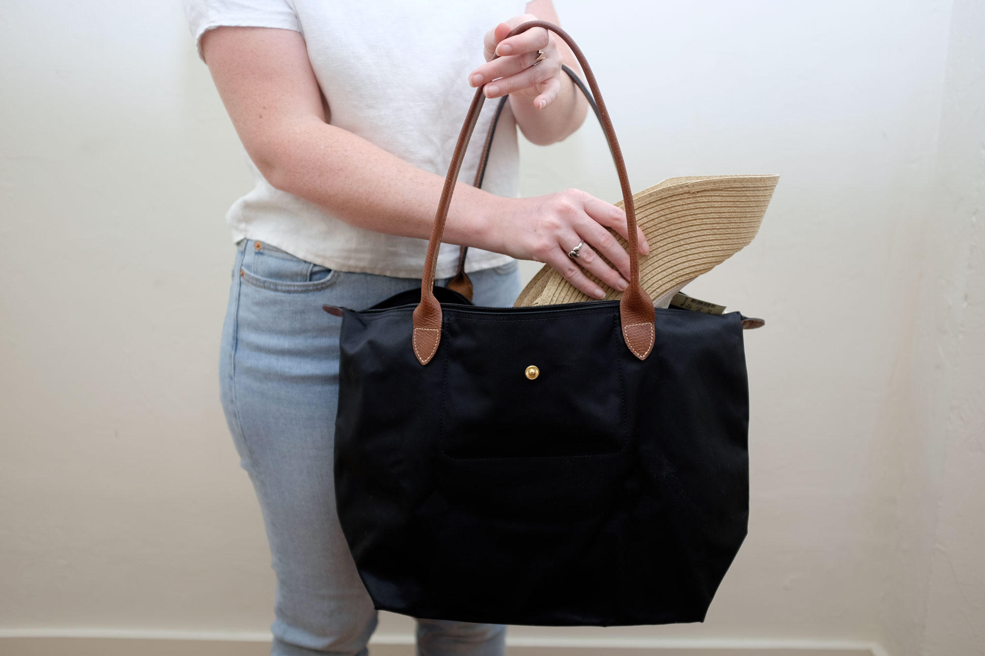 Alyssa folding a hat and placing it in her tote bag