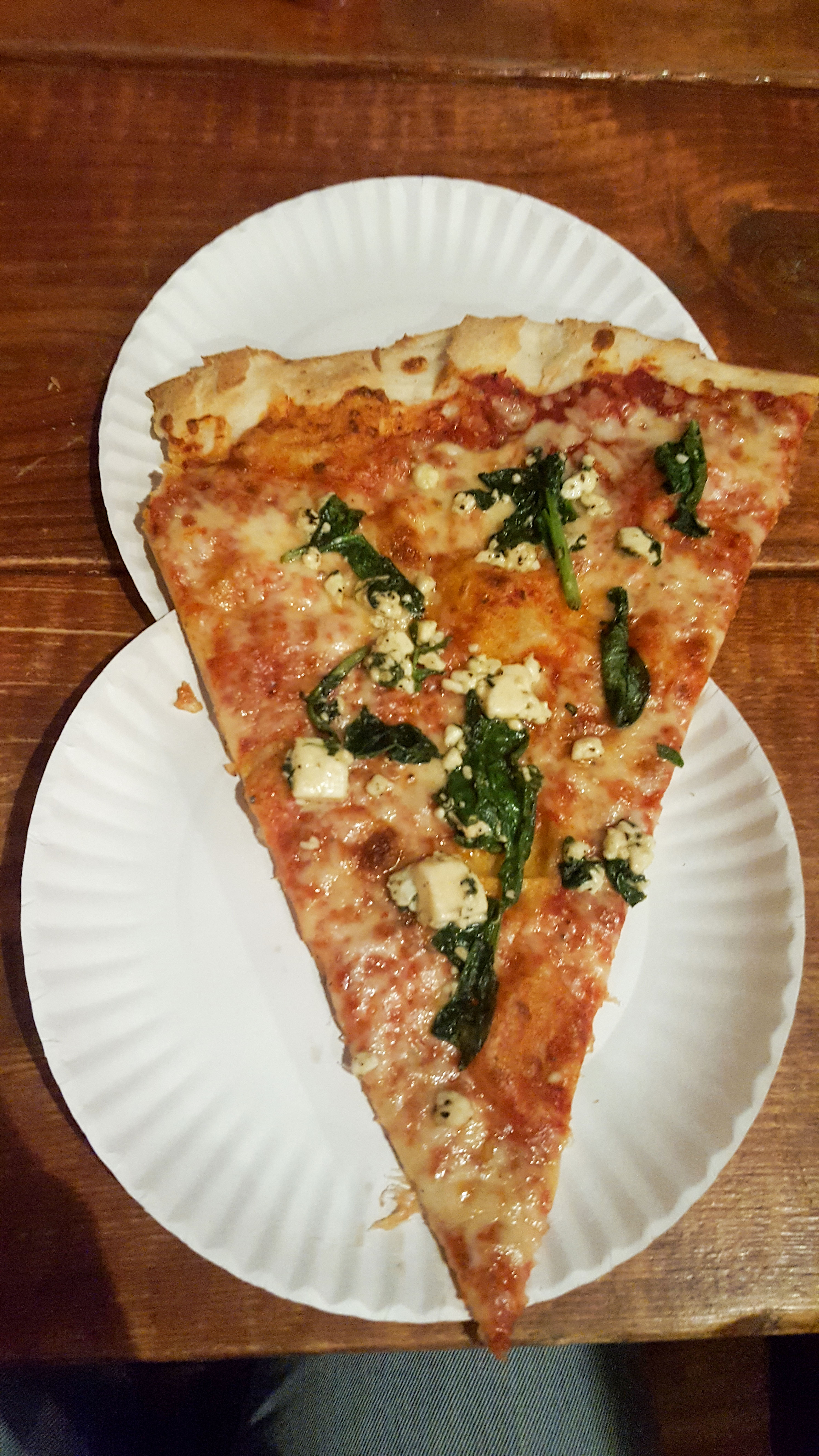 Very large slice of pizza set on two paper plates