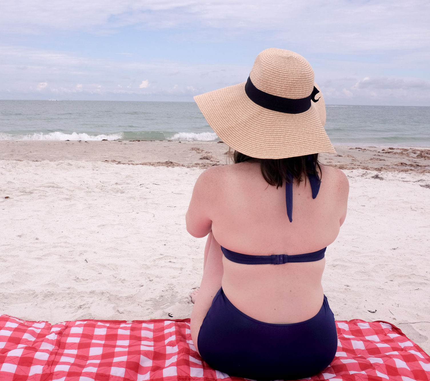 Krystal sitting on a towel looking at the water