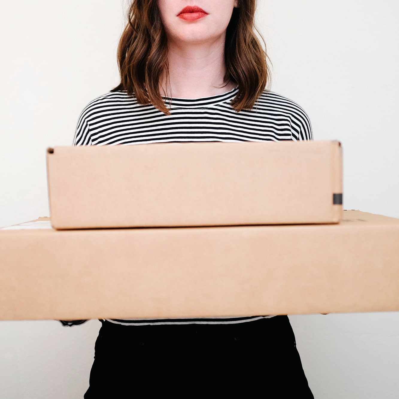 Krystal holding boxes while wearing a striped tee