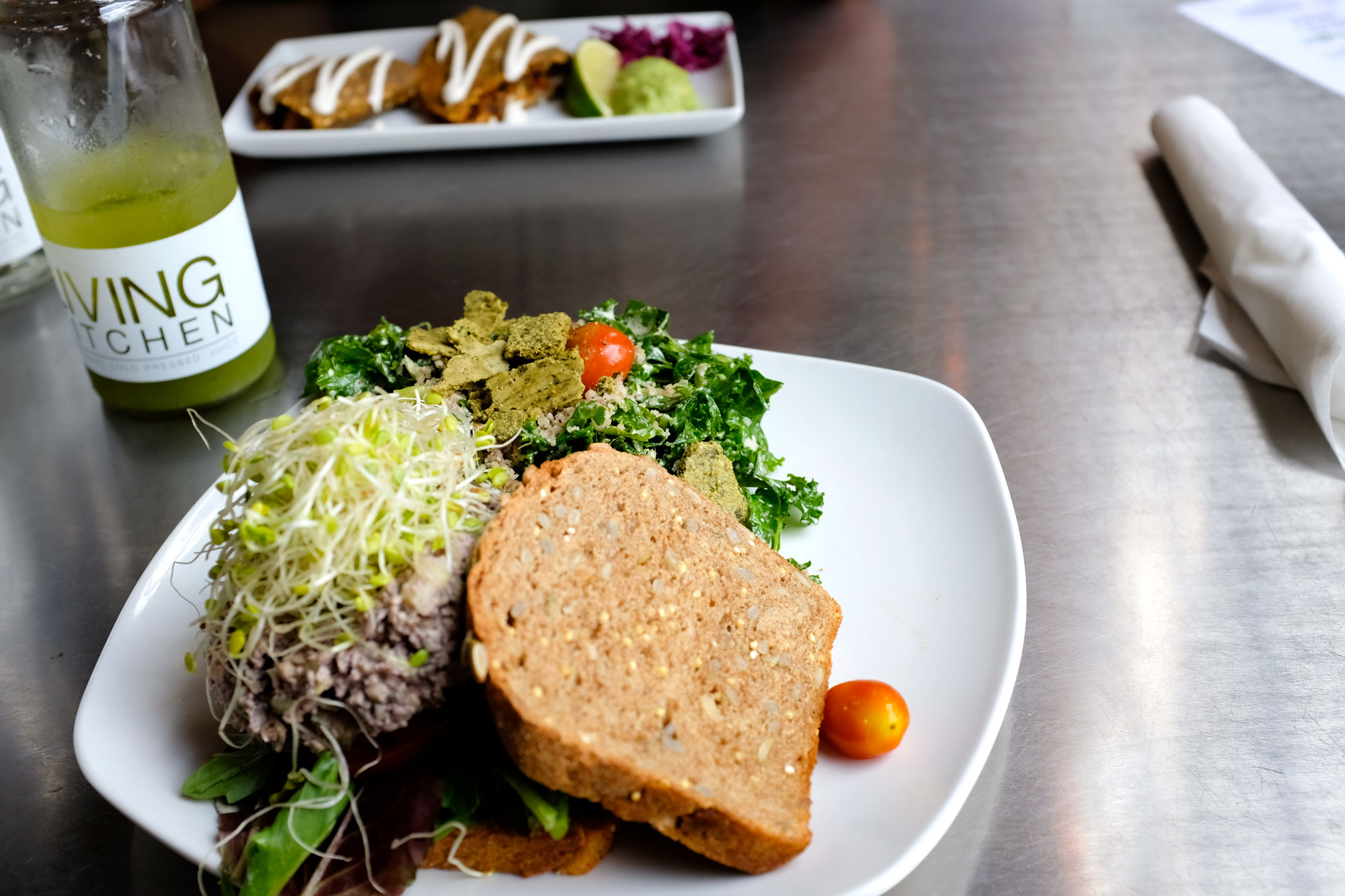 plates of food at living kitchen: one is a vegan sandwich and the other is a vegan quesadilla. Most of the food is green, including the kale lemonade!