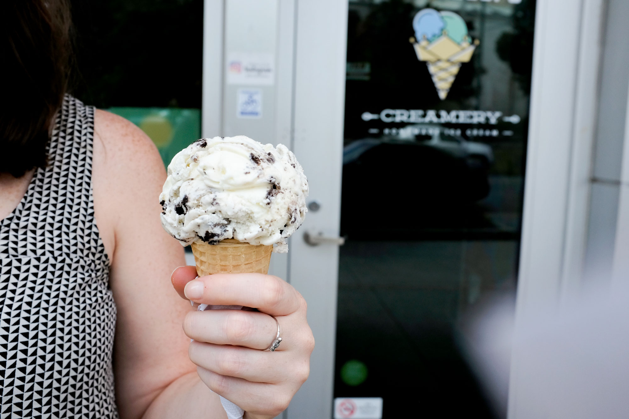 Krystal holding a cone of ice cream in front of the shop's door