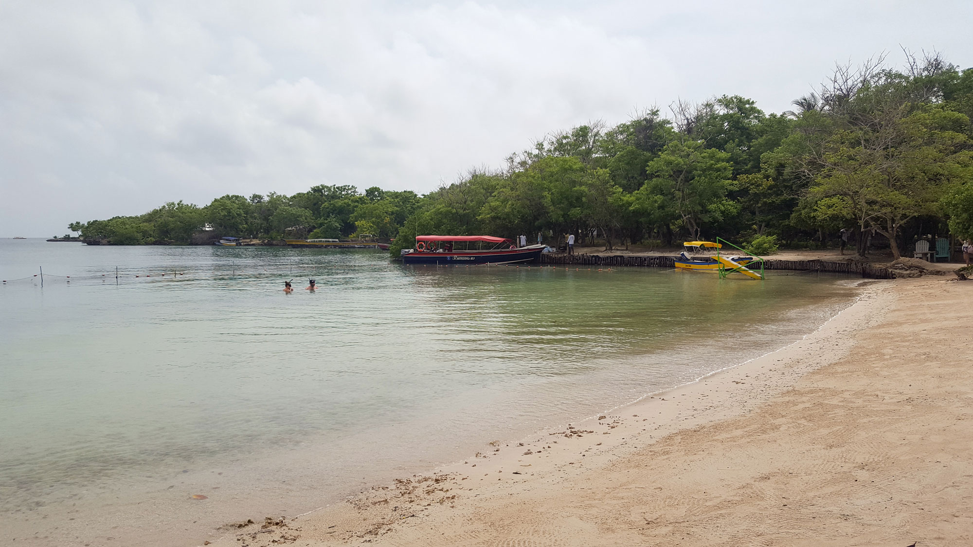 View of the shore at Islabela; the boat and dock are in the distance, and there are two people in the water