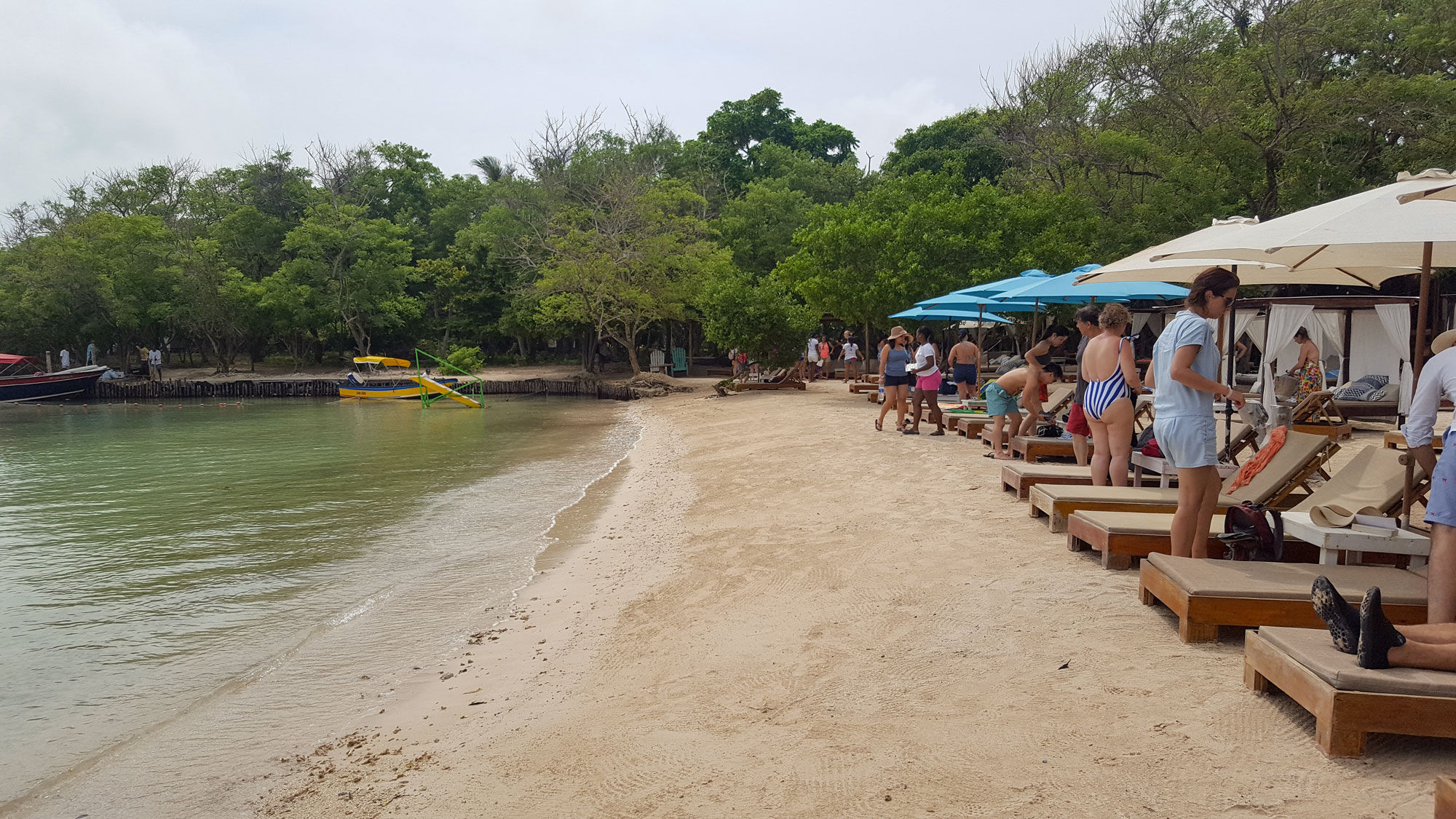 View looking down the sandy beach; the water is on the left, and a row of chairs and guests is on the right