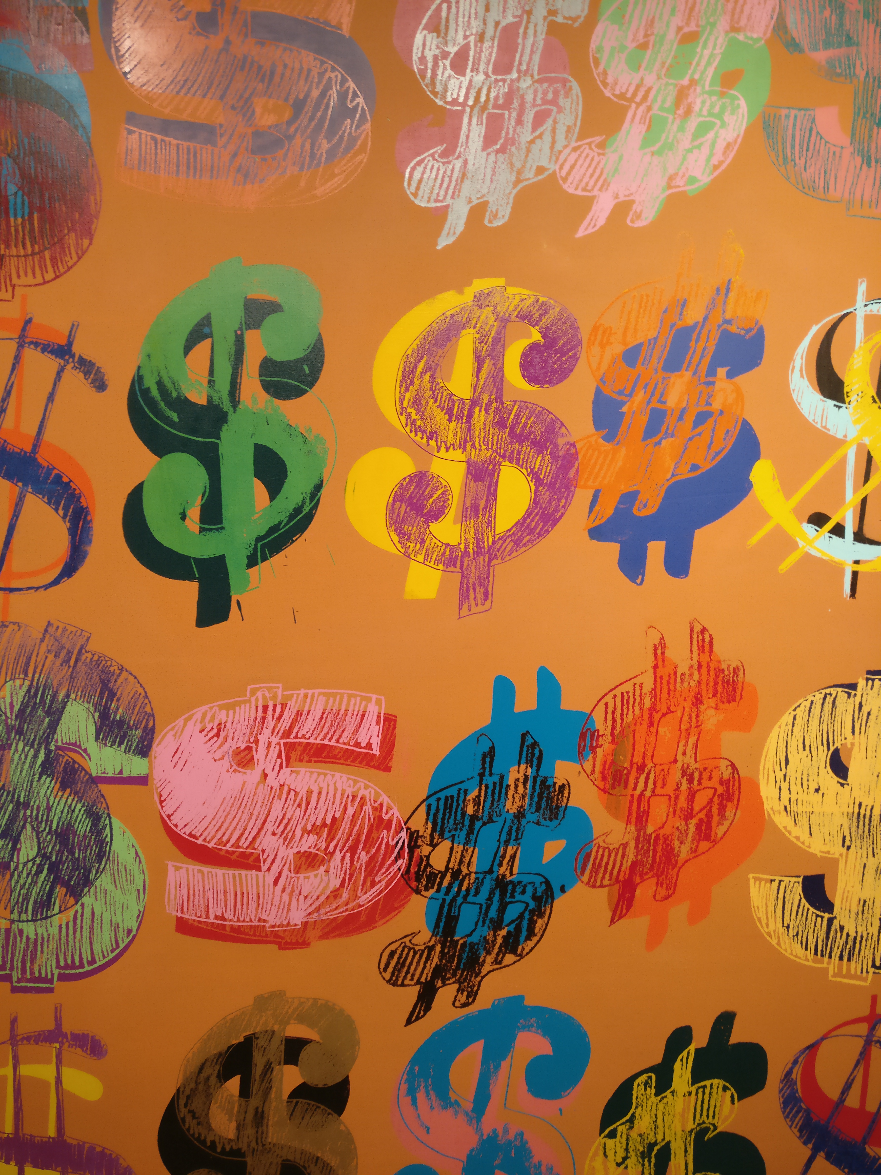 Photo of an Andy Warhol painting with an orange background and dollar symbols