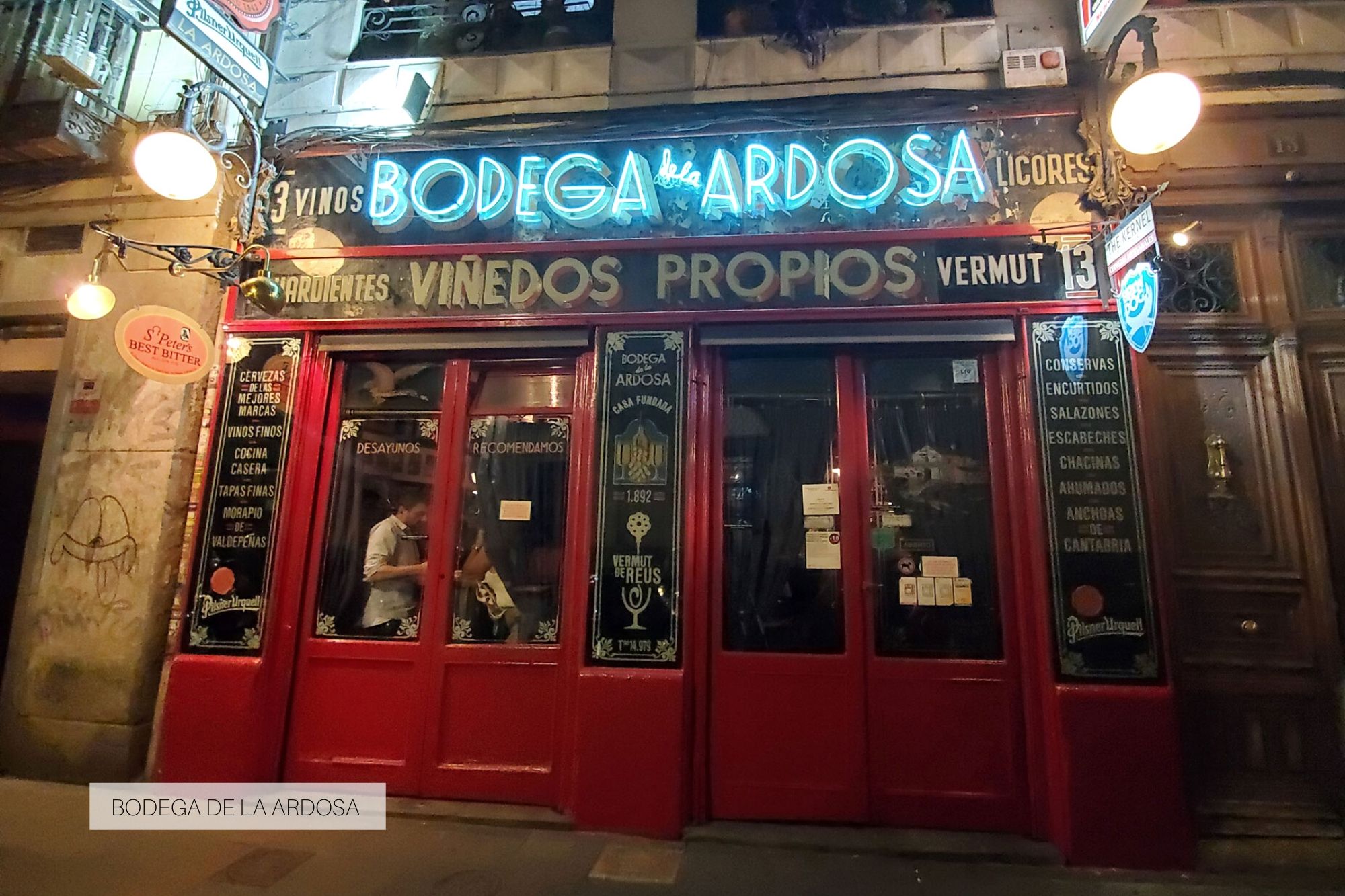 Exterior of Bodega de la Ardosa; it's busy inside and the lights are a neon blue