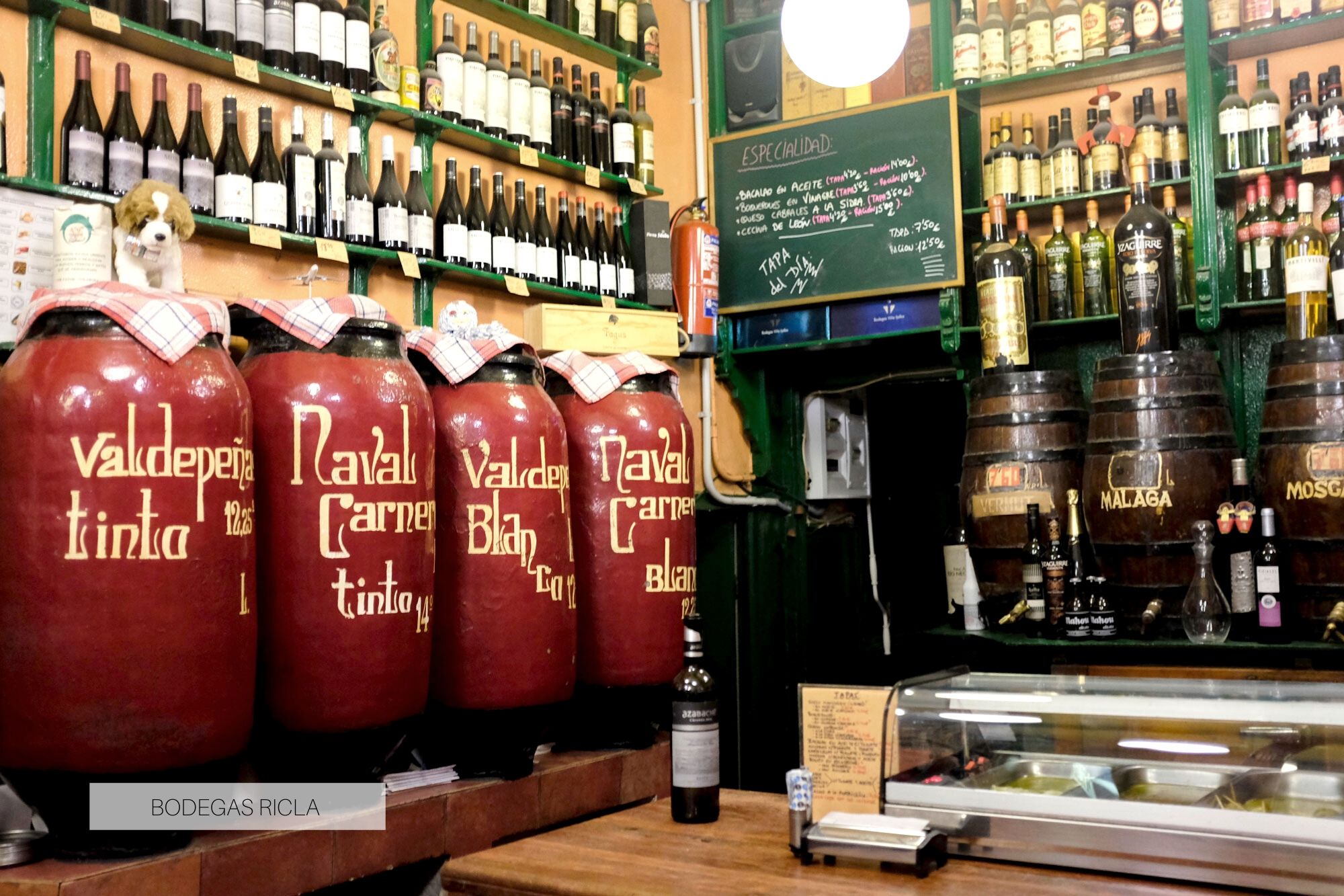 Interior of bodegas ricla; there are large barrels and bottles of wine on the walls