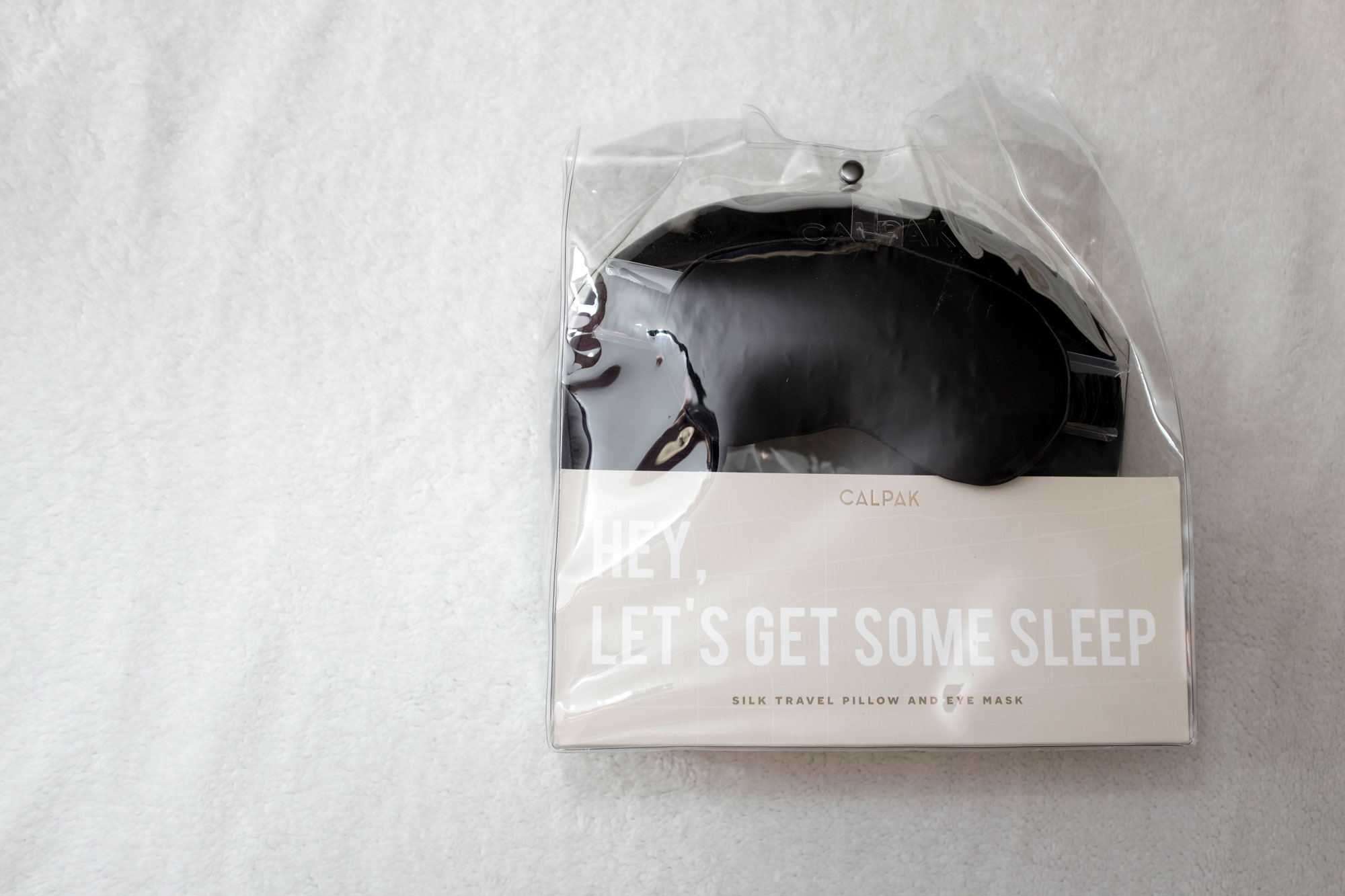 Photo of the silk travel set as it arrived; the pillow and mask are visible through the clear square plastic case