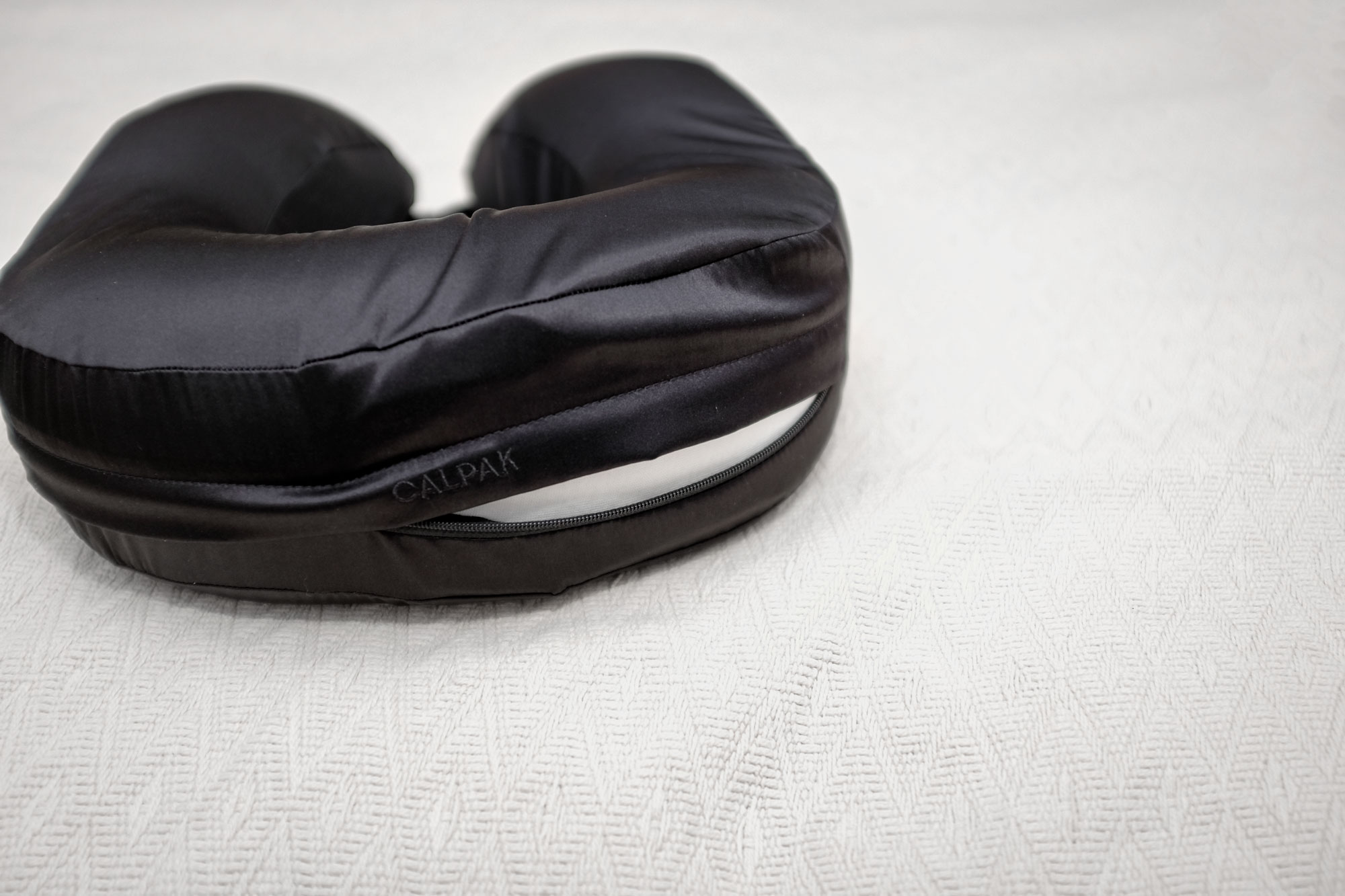 The CALPAK pillow slightly unzipped to reveal the inner cushion.