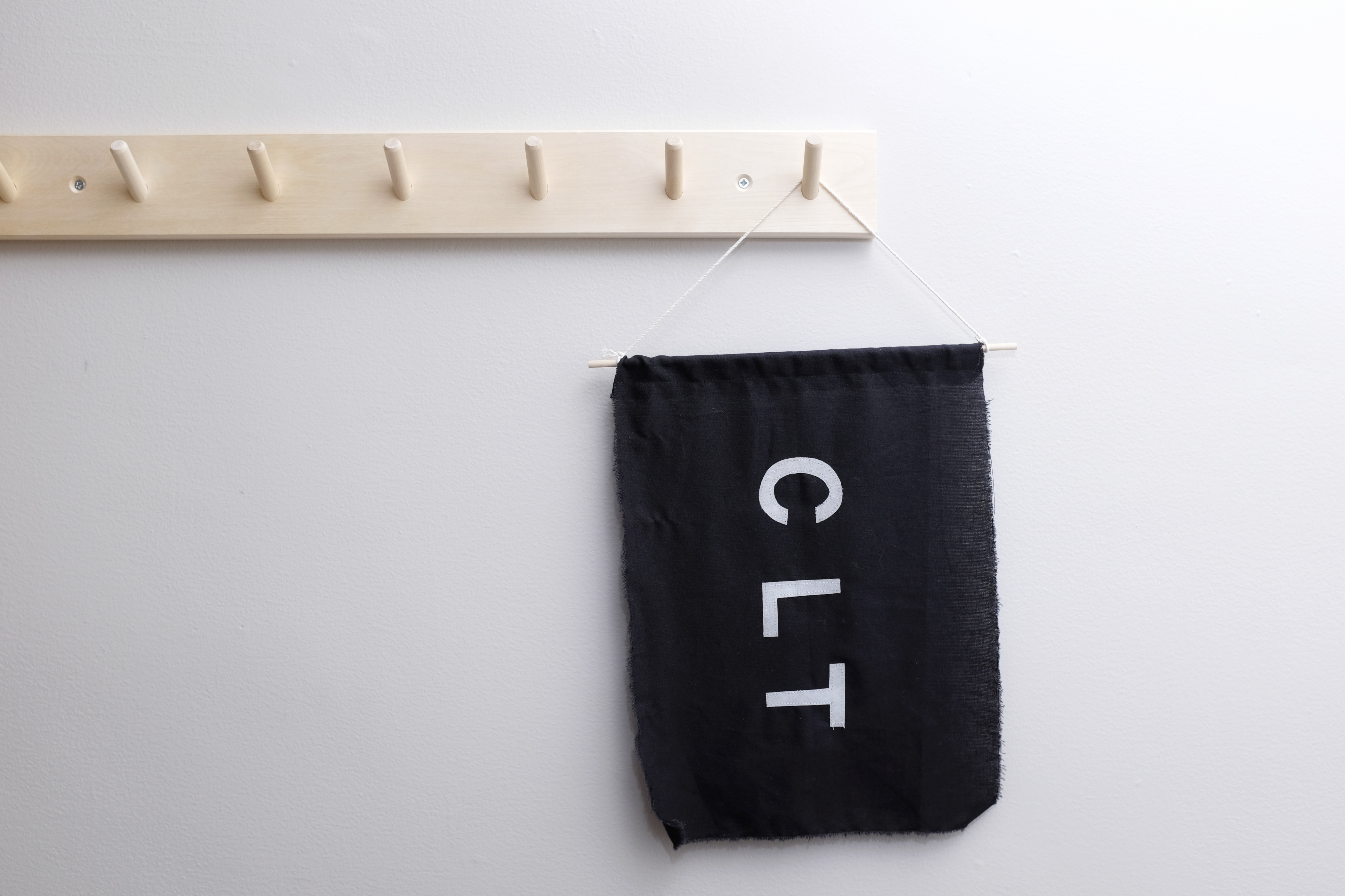 Banner that says "CLT" on a wooden peg rail