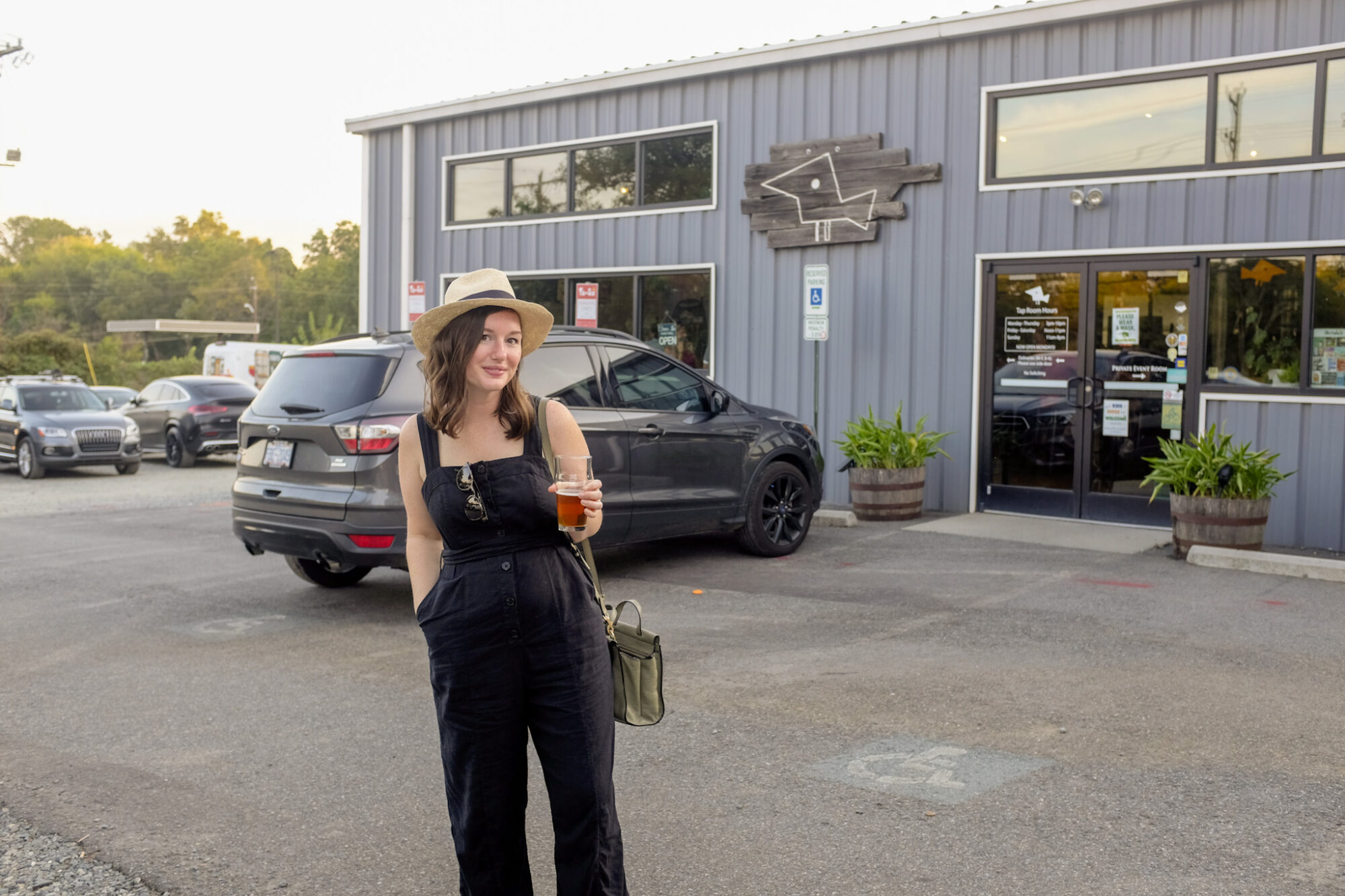 Alyssa stands outside of Birdsong Brewing with a beer