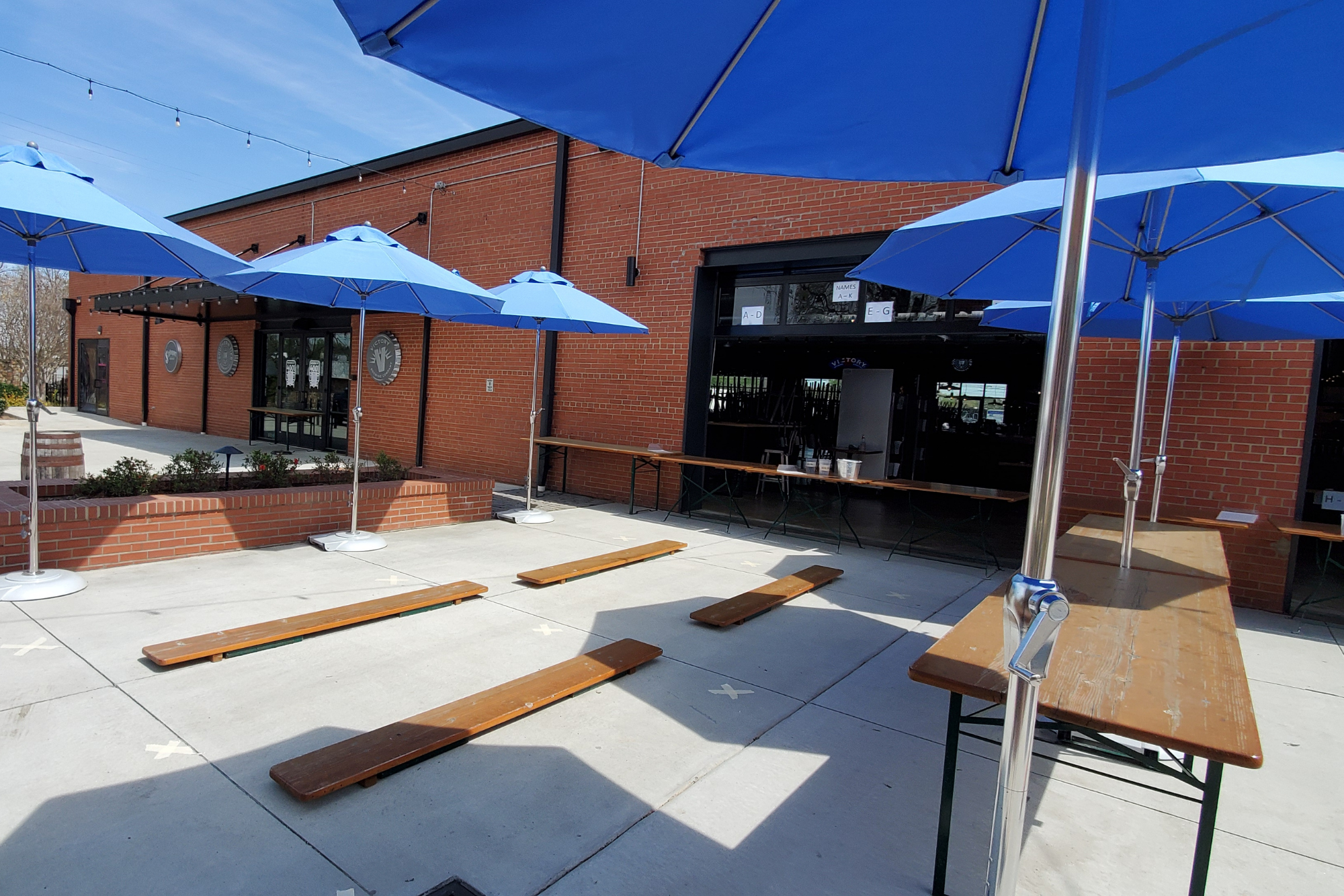 Exterior of a brick building with tables and umbrellas in front