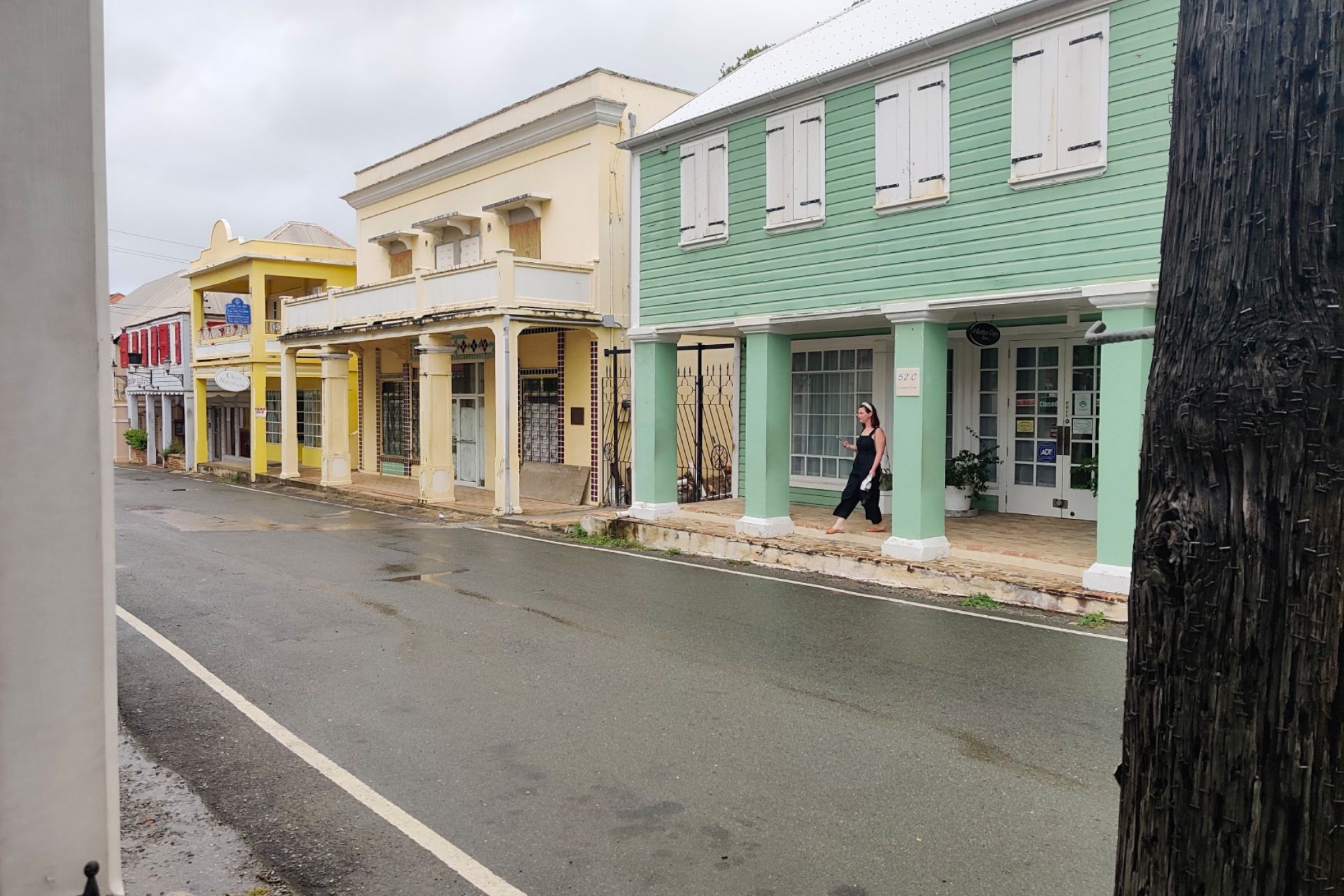 Pastel colored buildings across the street; Alyssa is in front of a green one