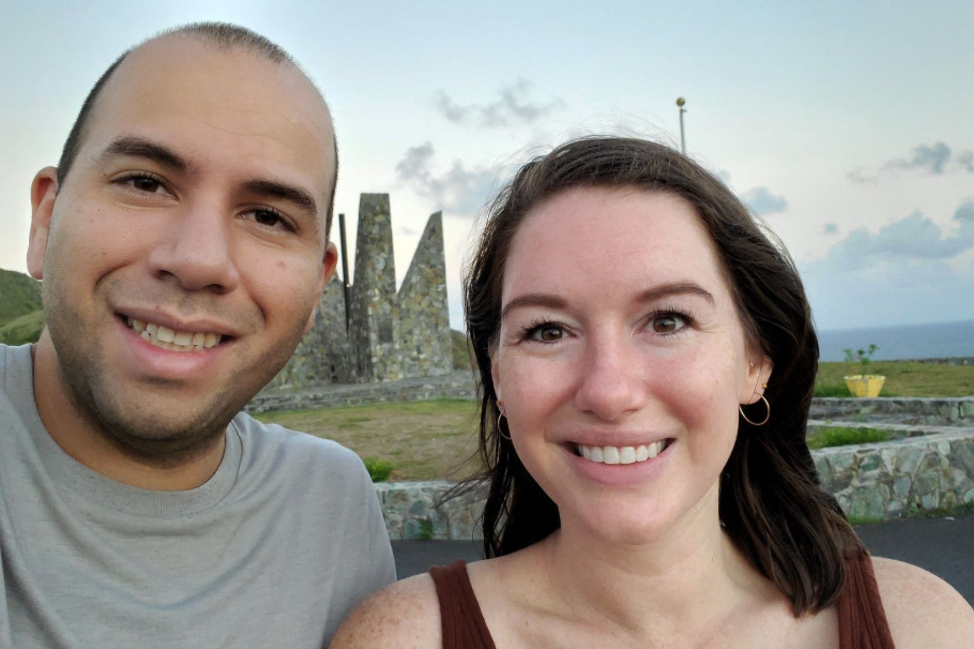 Michael and Alyssa are in front of a pointy monument made of stone and arranged in a circle