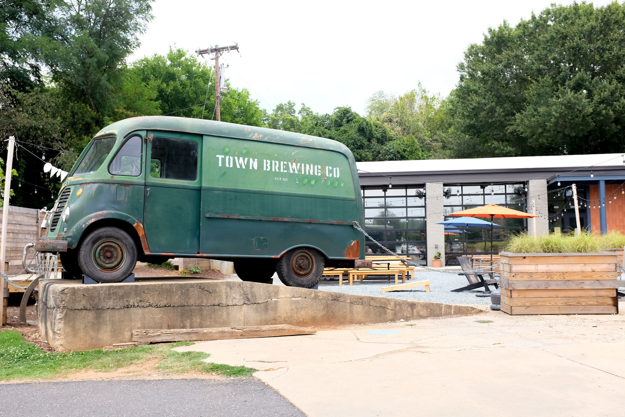 A green vintage van that says Town Brewing Co sits in front of an industrial-looking building