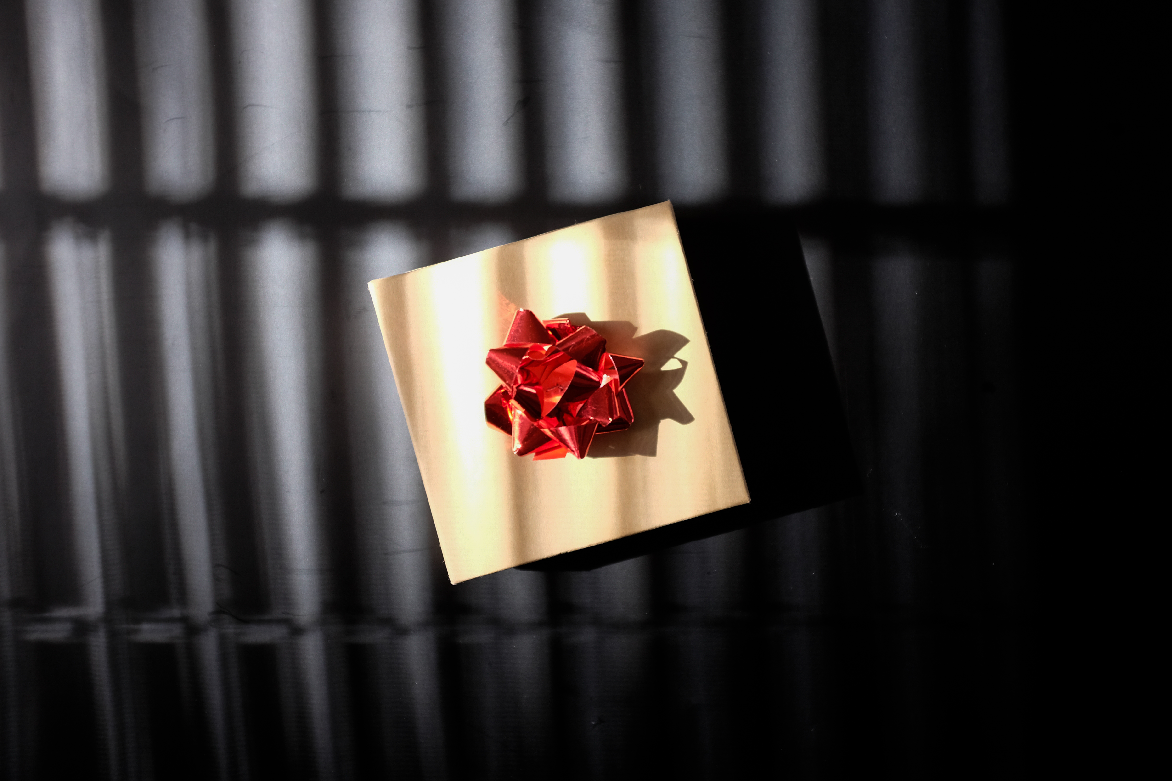 A brown paper package with a red bow on a black background