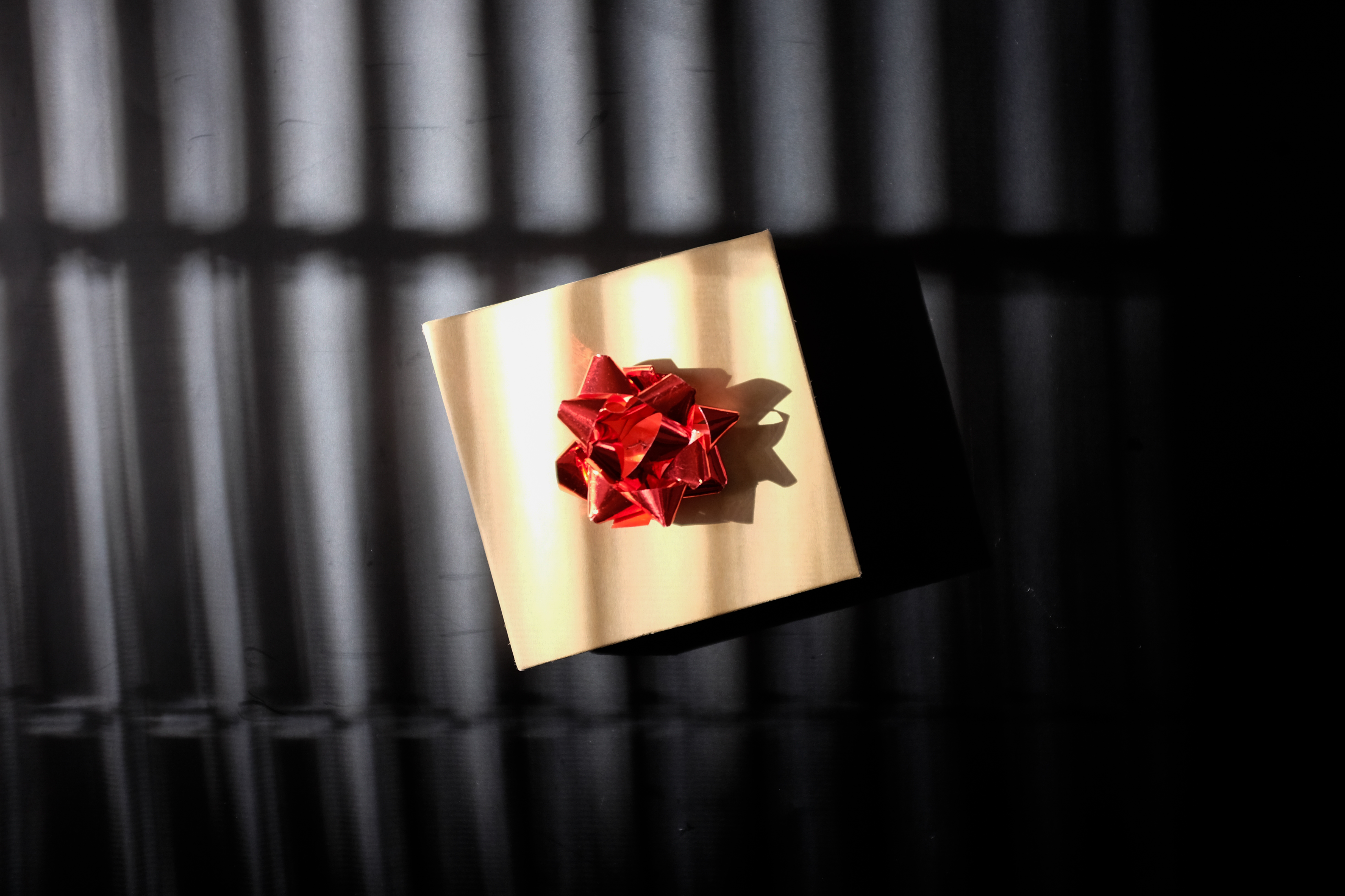 A brown paper package with a red bow on a black background