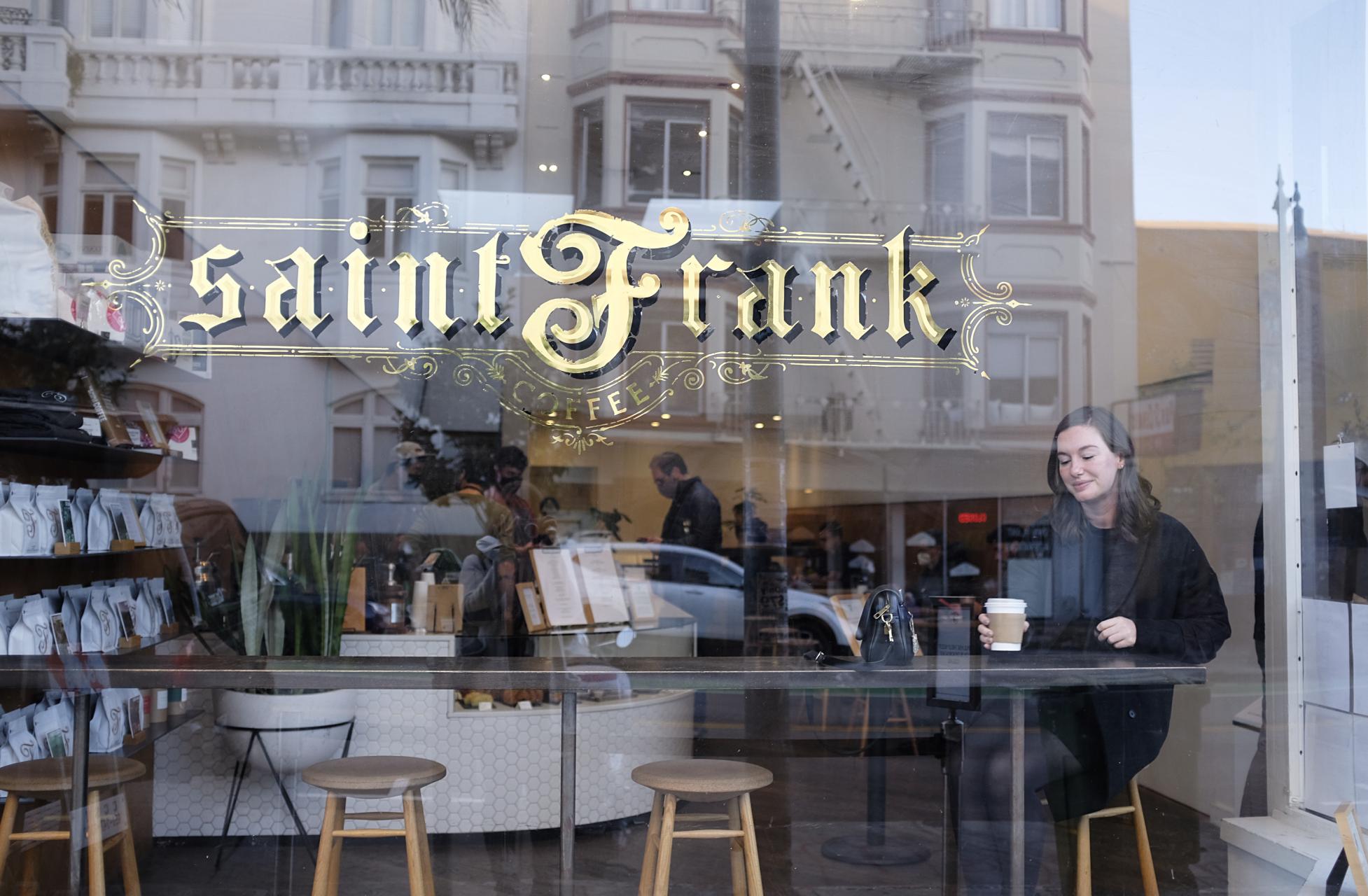 Alyssa sits in the window of Saint Frank, with a cup of coffee