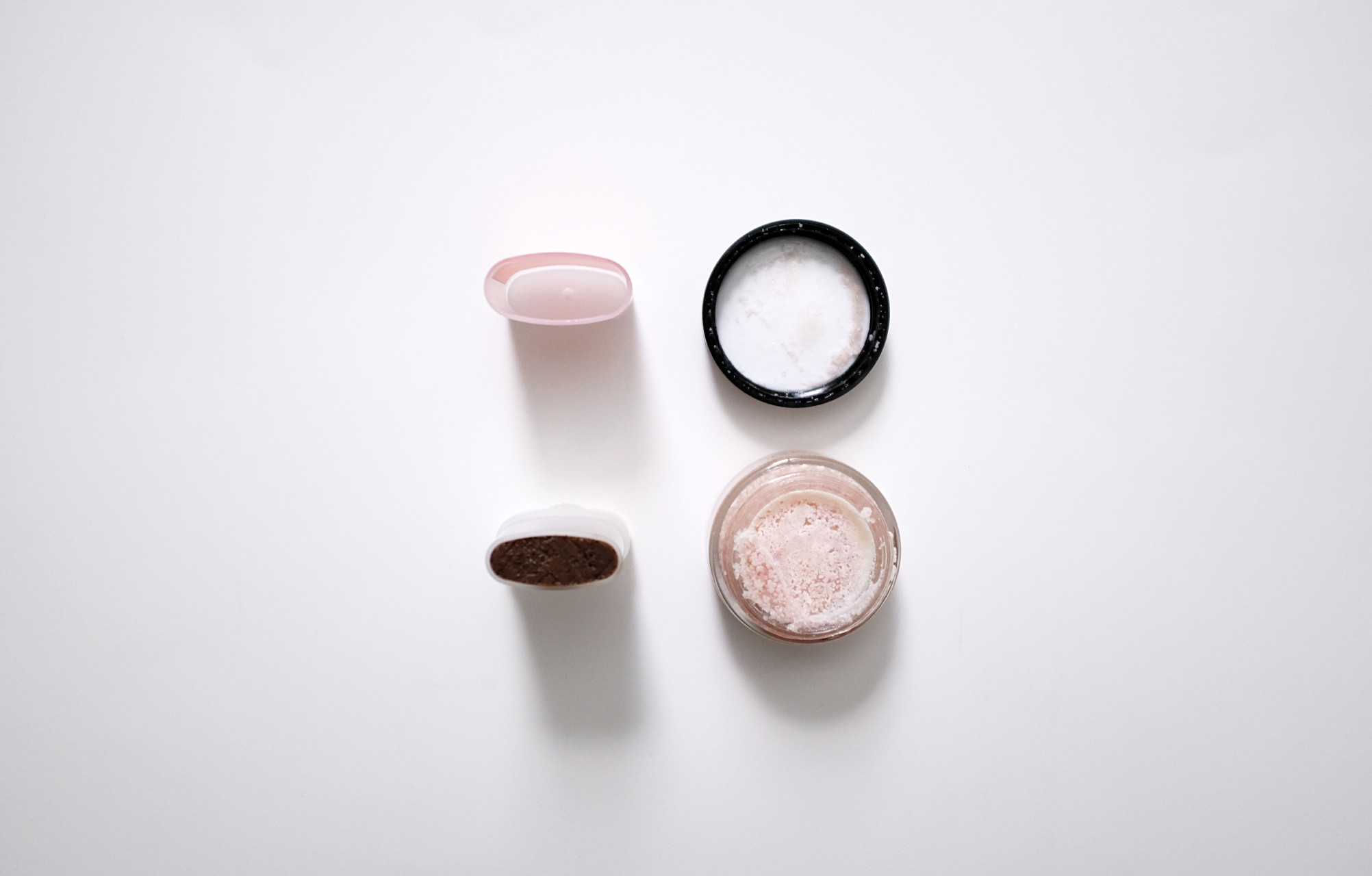 Two open beauty containers: on the left is the open tube of Olio E Osso Lip Scrub, and on the right is the FRENCH GIRL Lip Polish