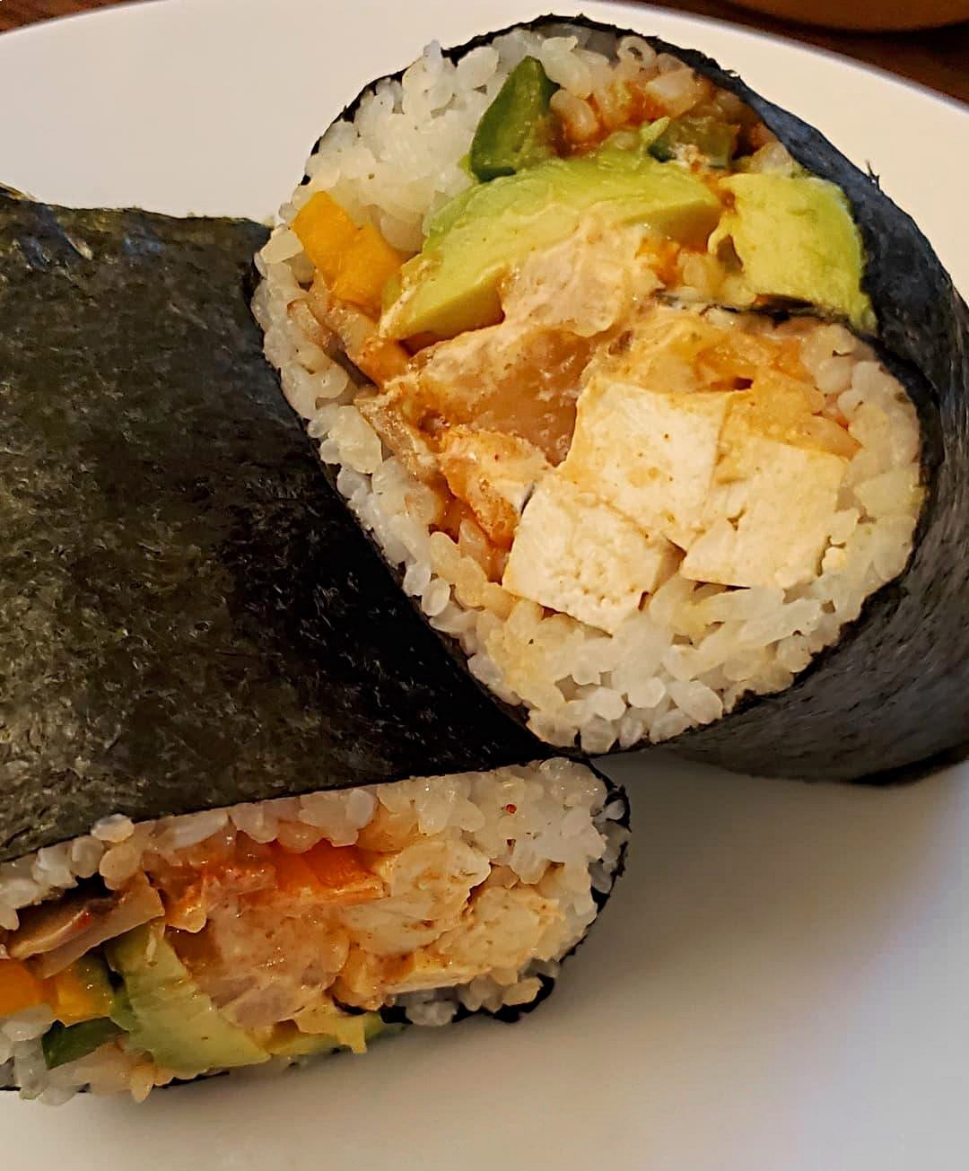 A sushi burrito filled with veggies and tofu
