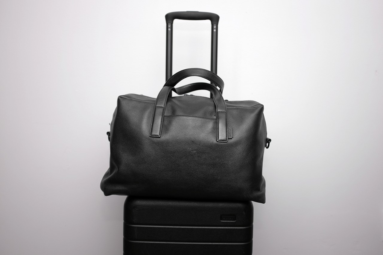 The black leather Everywhere bag sits on top of the carry on suitcase from Away