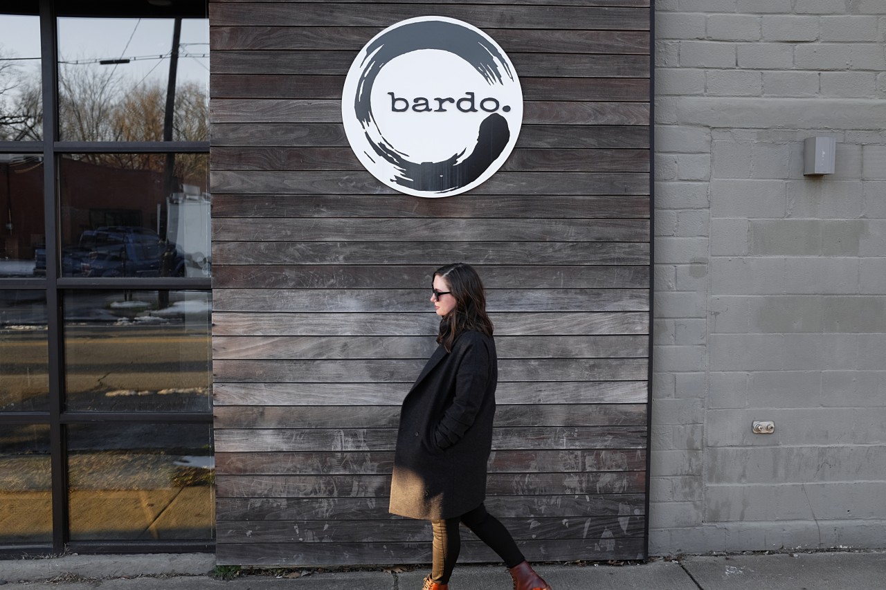 Alyssa walks underneath the sign for Bardo in Charlotte