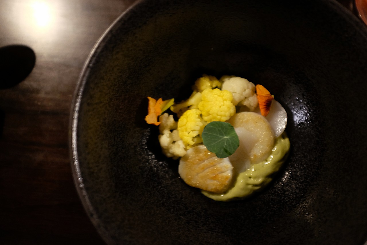 Dish of scallops, green curry, cauliflower, and nasturtium