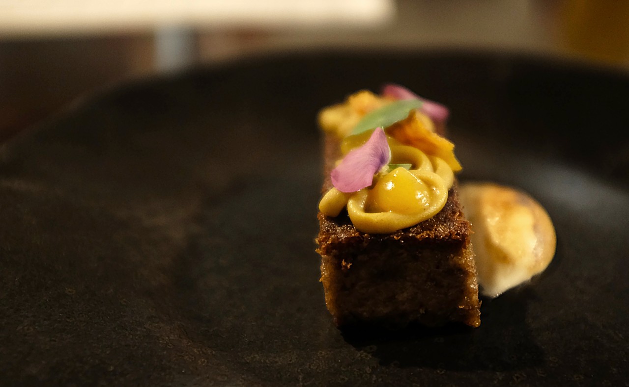 Rectangle of pork topped with persimmons and leaves, set atop a bruleed foam