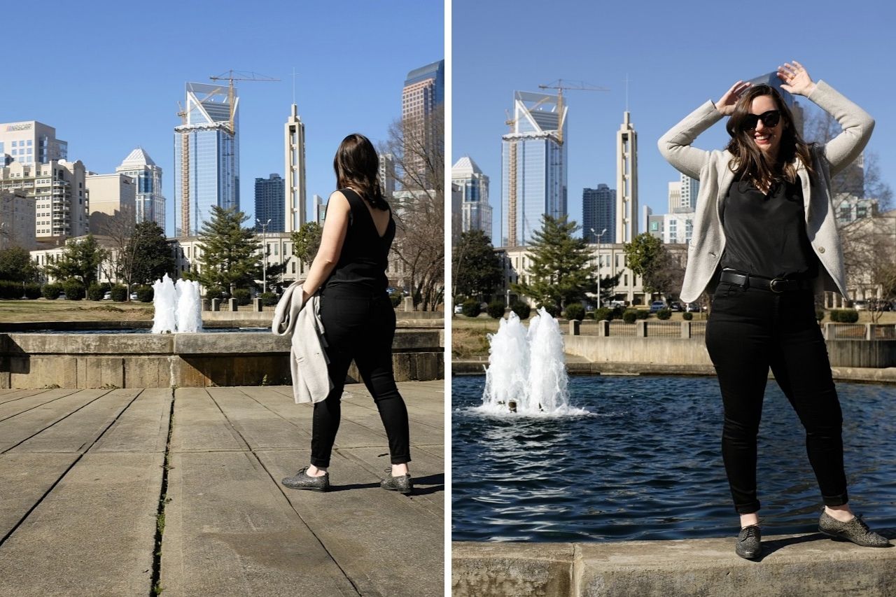 Alyssa stands near the edge of a fountain in front of the Charlotte skyline. She is wearing a black top, black jeans, a grey sweater, black Oxfords, and black sunglasses