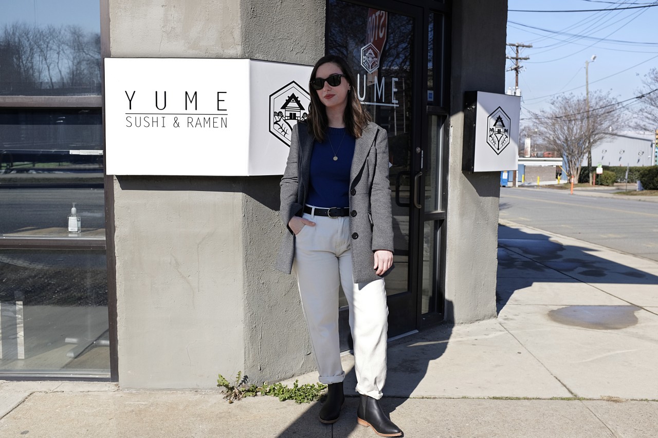 Alyssa stands in front of the sign outside of Yume