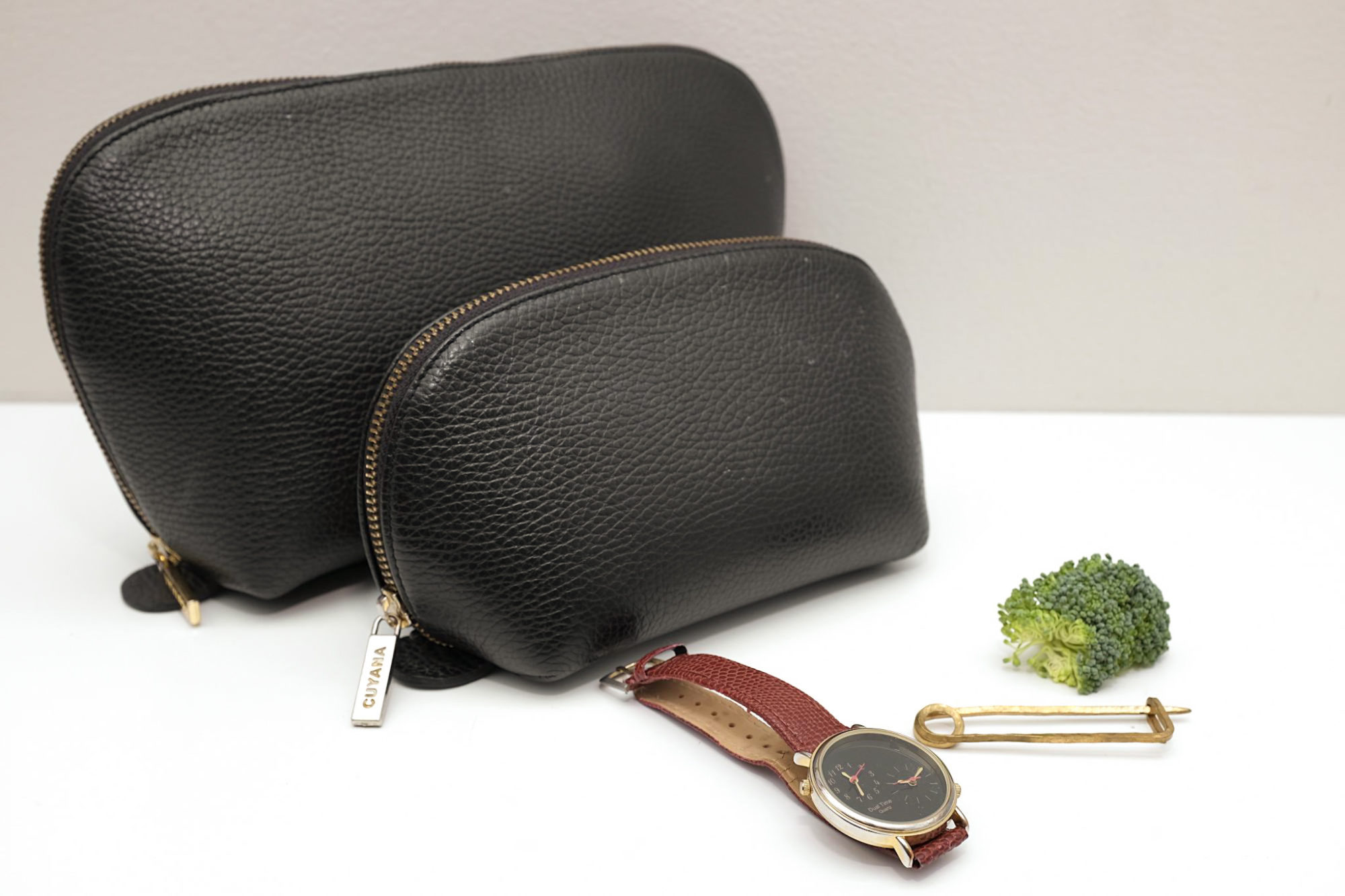 The leather travel set sits on a white bench with a watch, safety pin, and a piece of broccoli (this last item is an homage to an image in the previous post that included an air plant - that plant is very long dead)