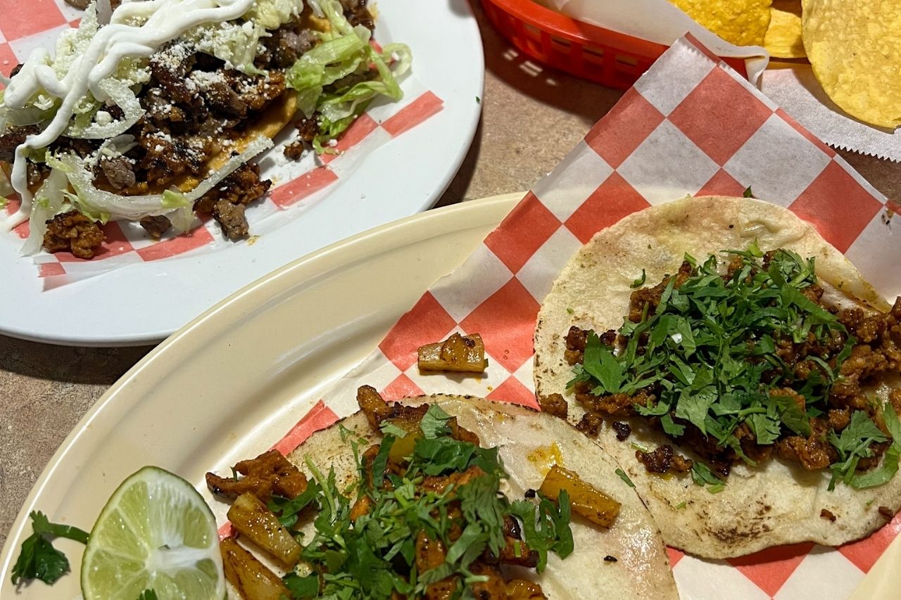 two tacos, a huarache, and chips on a table