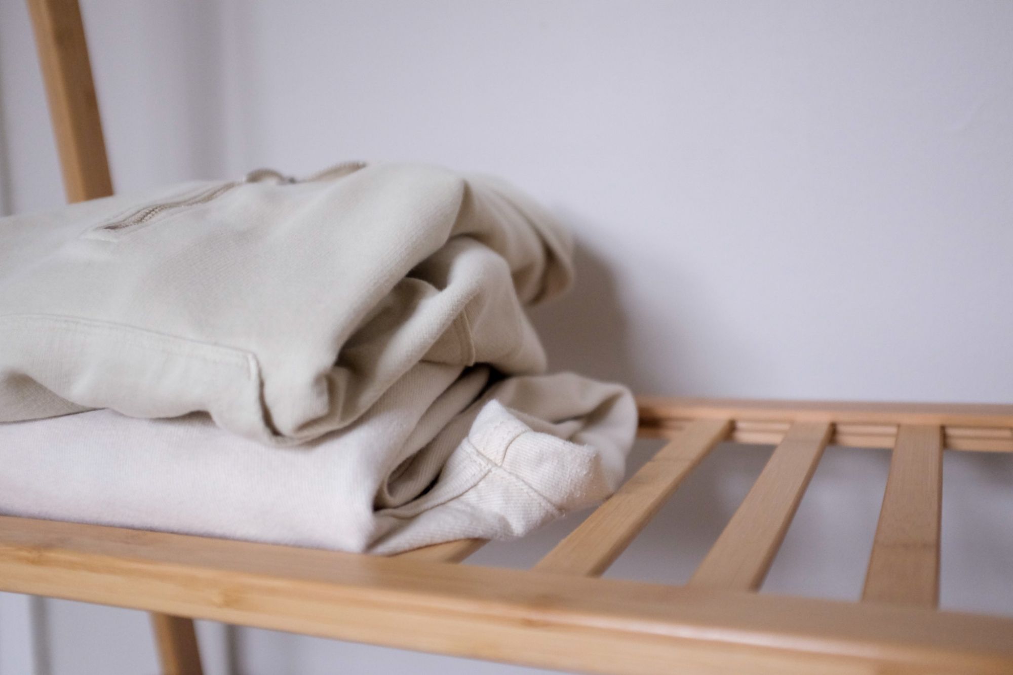 A light hoodie and light denim sit on a wooden rack