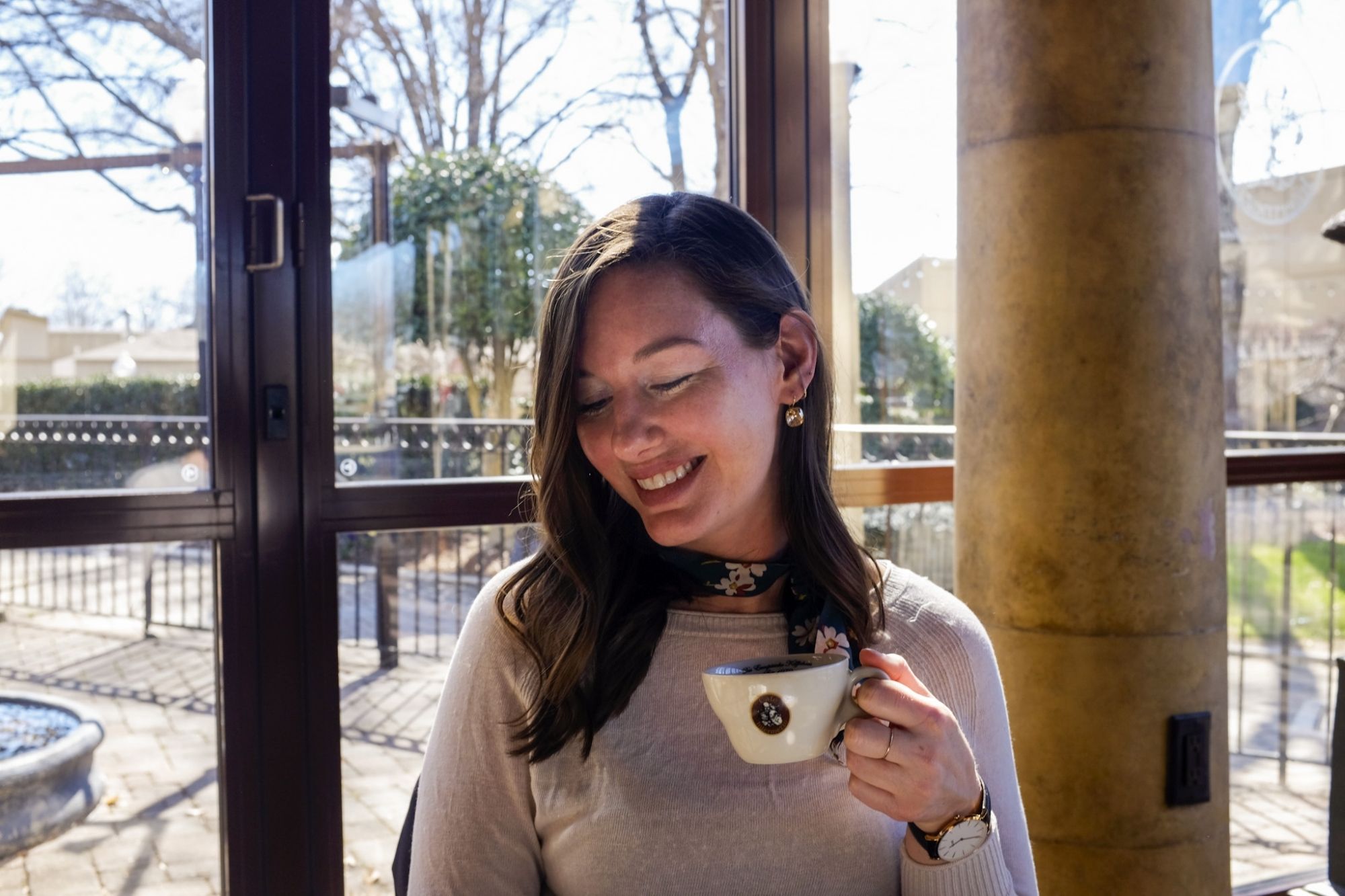 Alyssa holds a coffee and smiles while at Cafe Intermezzo