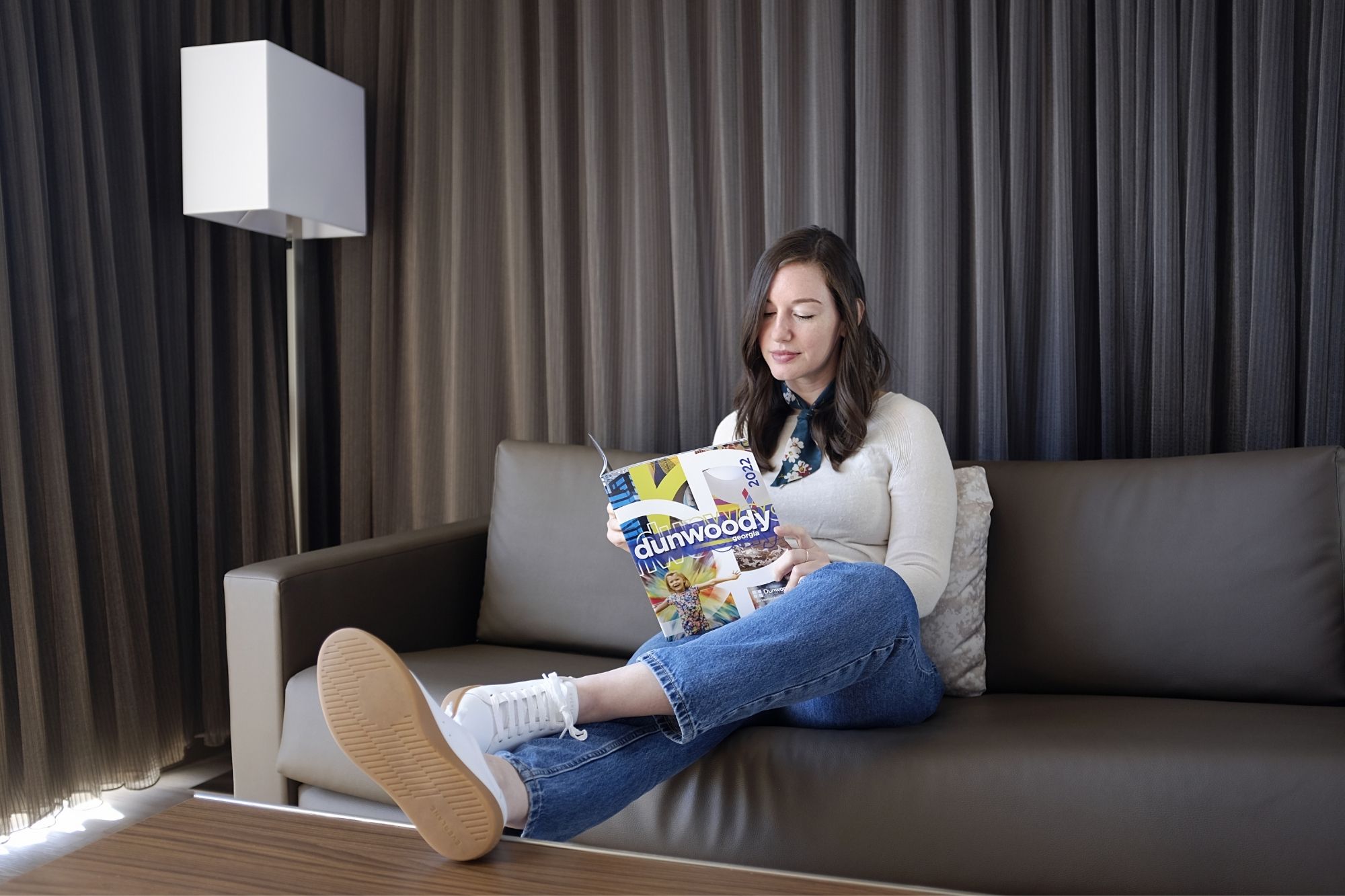 Alyssa reads the Discover Dunwoody guide in a hotel room