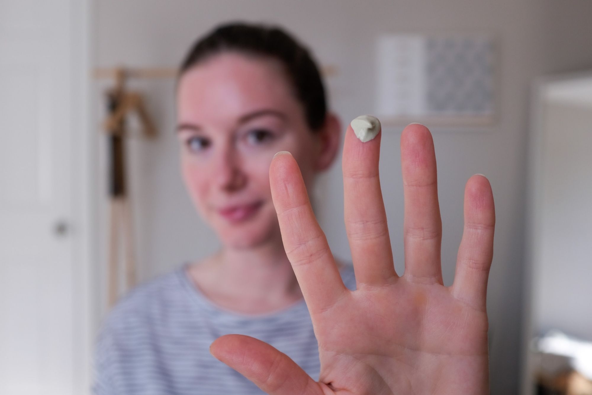 Alyssa holds her hand up to the camera; on one finger is a dime-sized amount of product