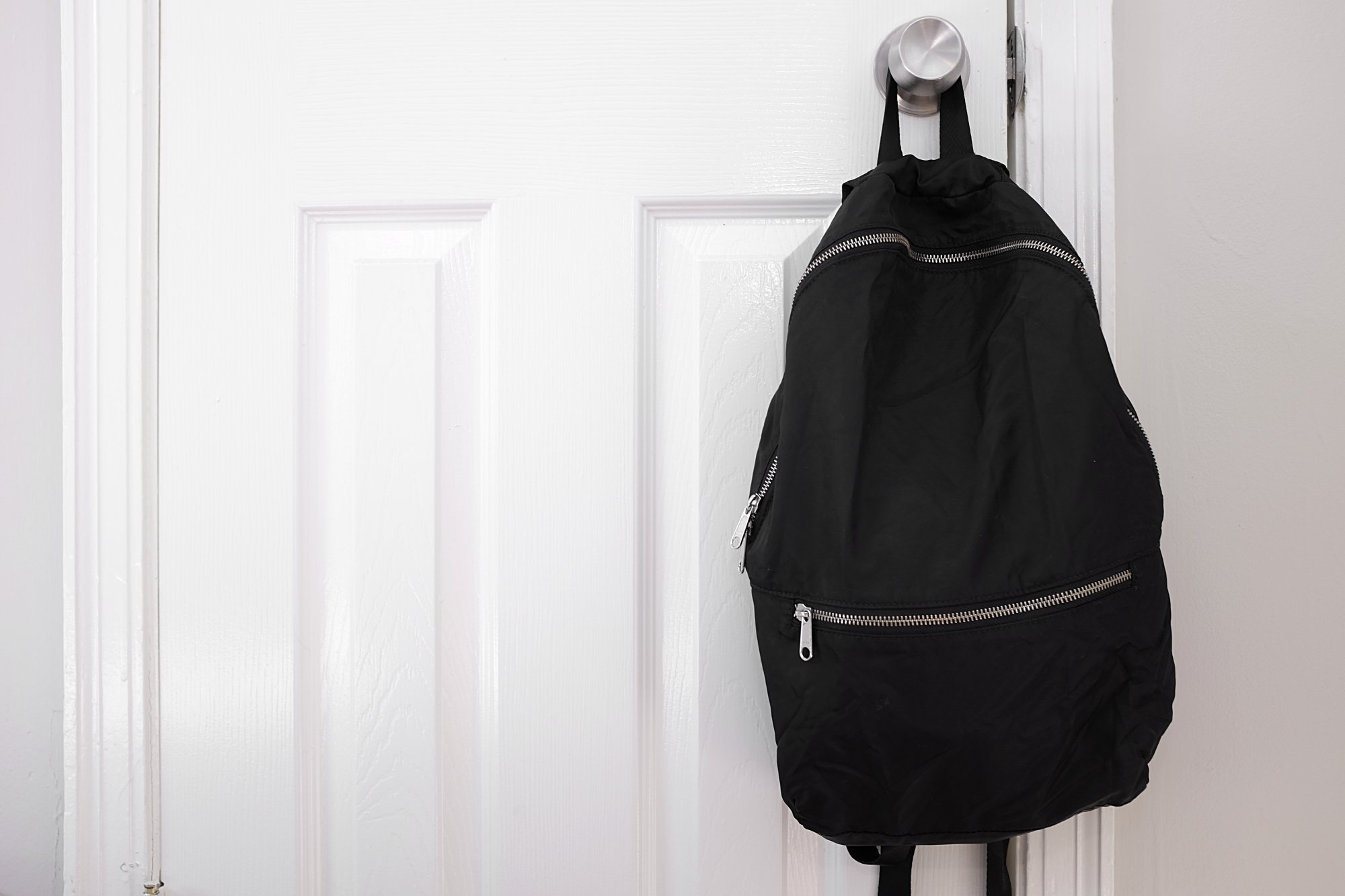 The packable backpack from Everlane hangs on a door handle