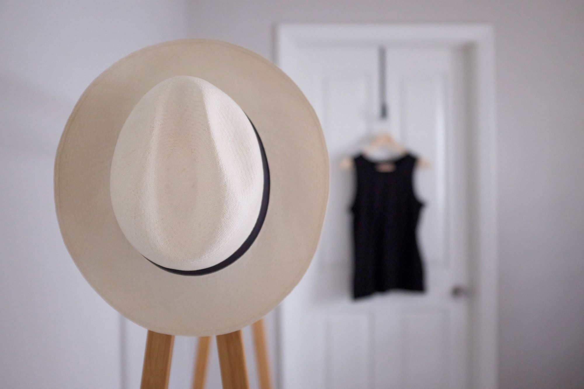 A Panama Hat sits on a wooden clothing rack