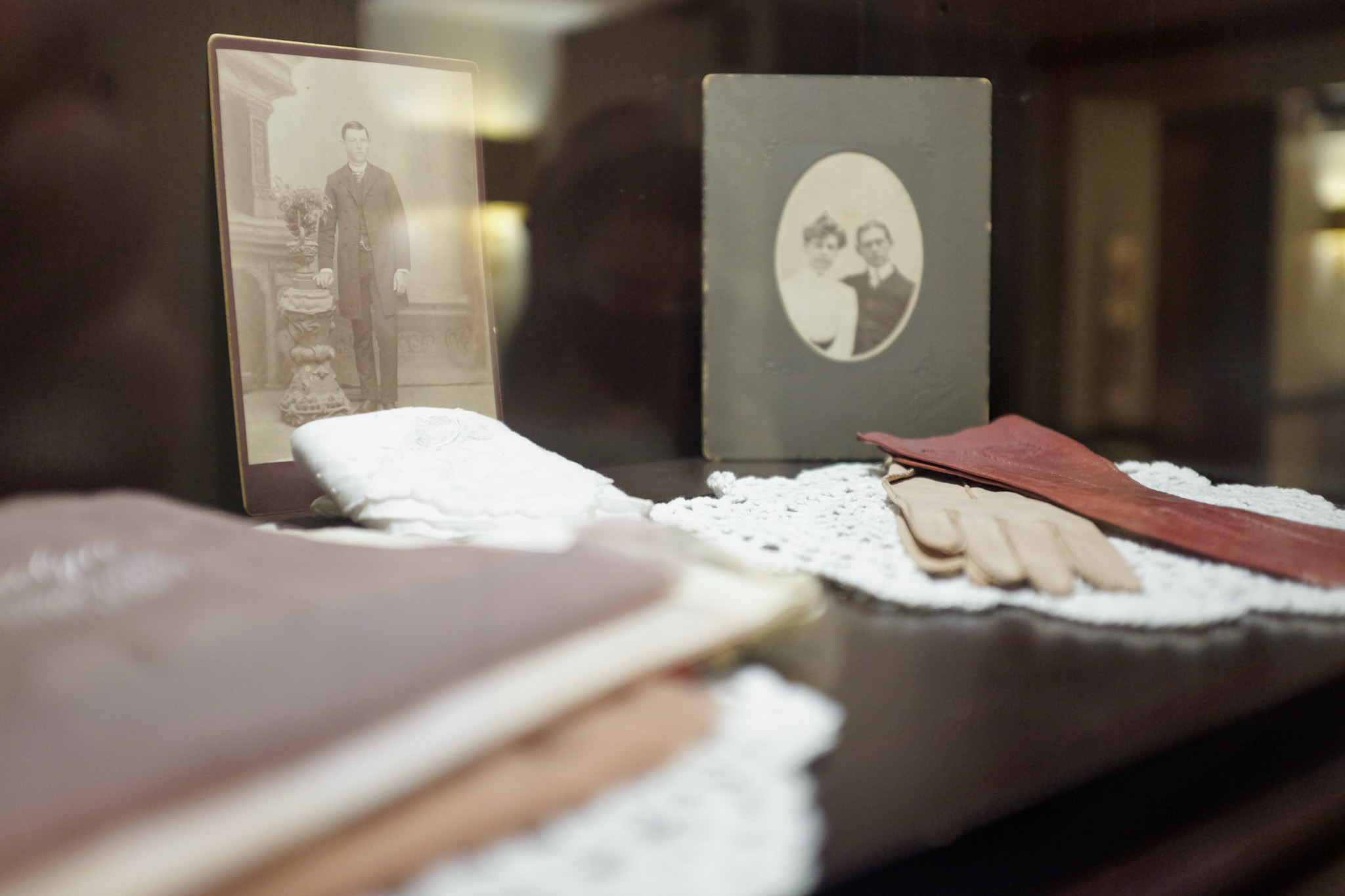 Pieces in a curio cabinet at the hotel - there are old gloves, papers, and black and white photos