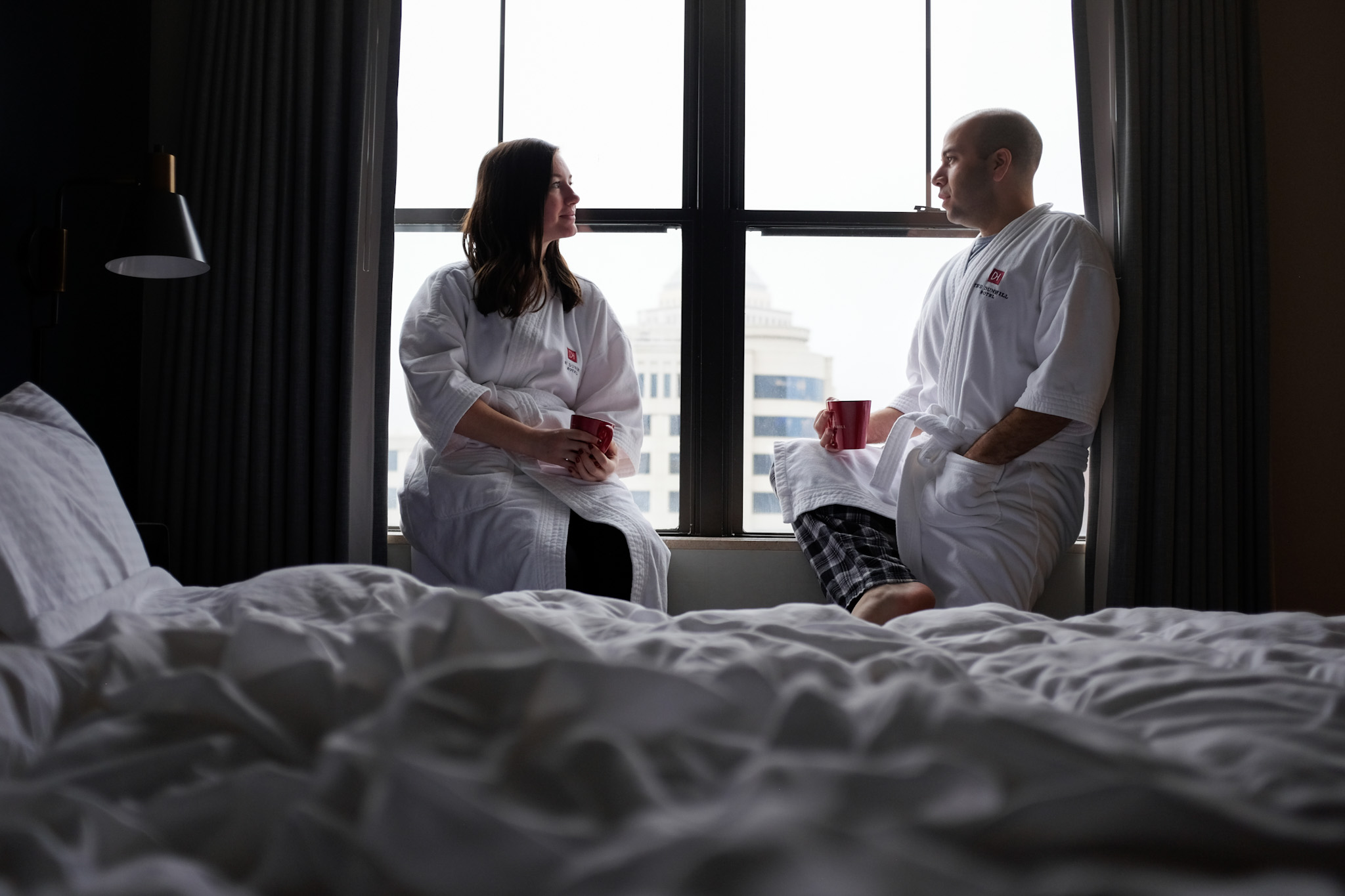 Alyssa and Michael sit in their robes in a window seat