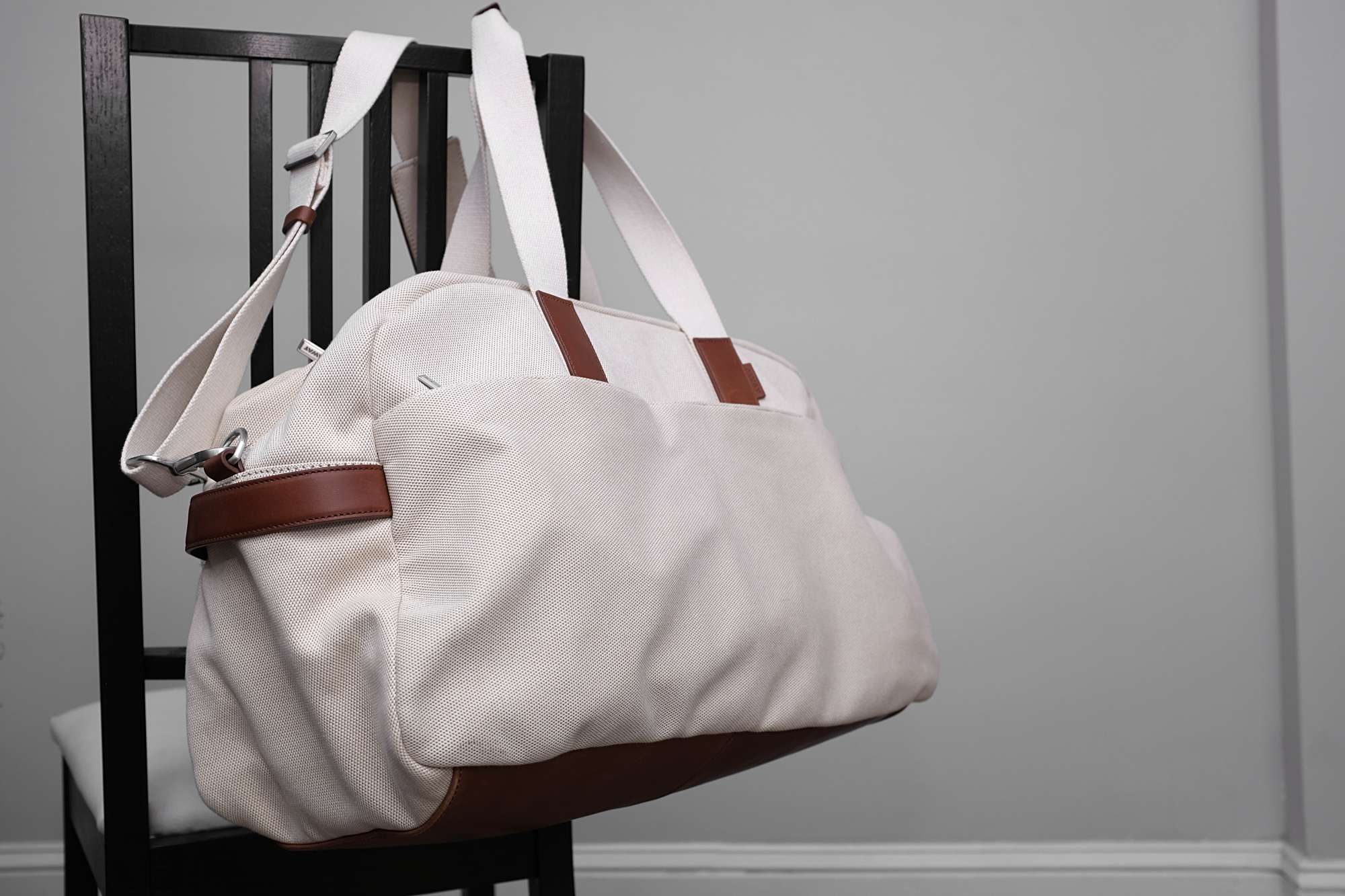 The weekender bag hangs from a chair