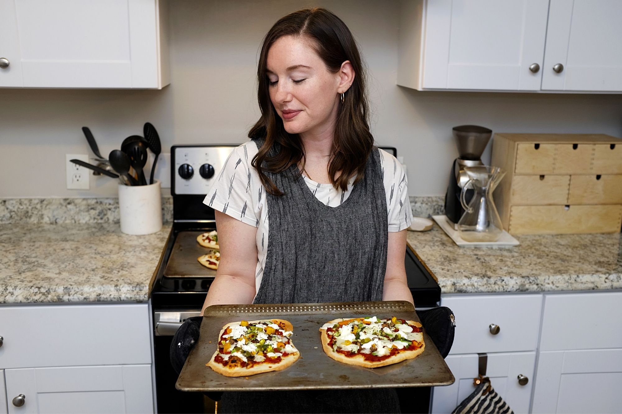 Alyssa holds a try with two finished pizzas