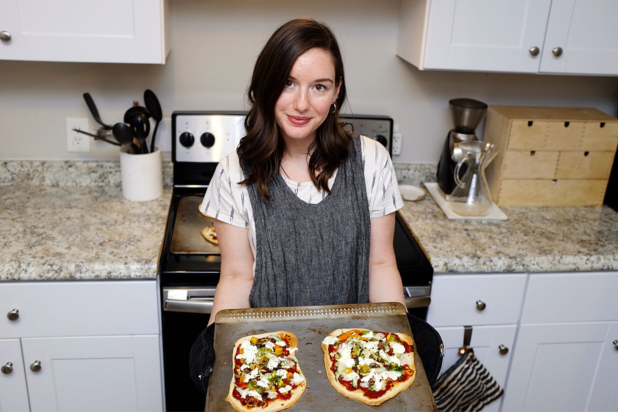 Alyssa holds a try with two finished pizzas